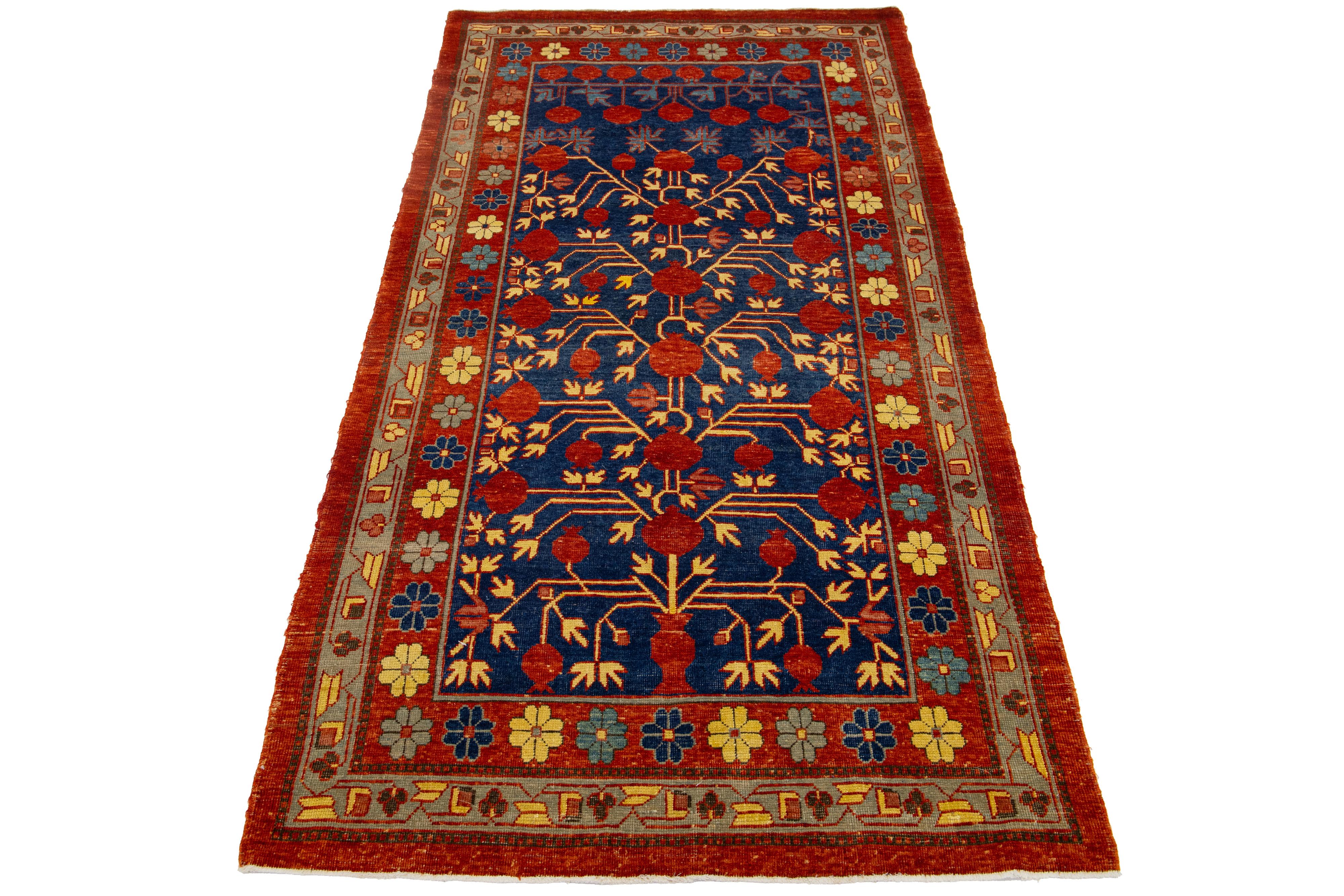 Schöner moderner Khotan Ton-in-Ton handgeknüpfter Wollteppich mit einem marineblauen Farbfeld. Dieses Stück hat beige und rostfarbene Akzente auf einem wunderschönen, miteinander verbundenen Granatapfel-Rosettenmuster.

Dieser Teppich misst 3'8