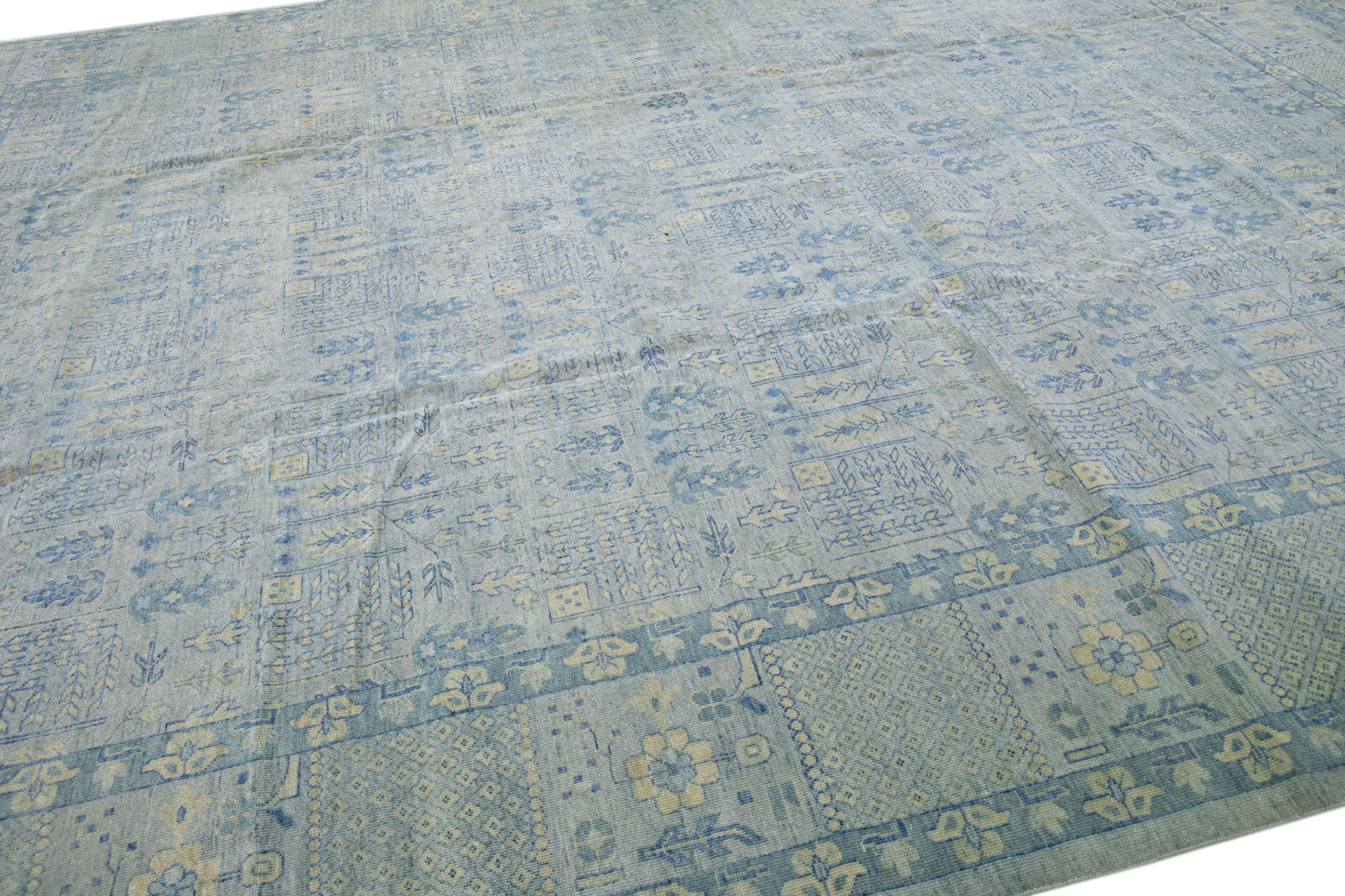 Magnifique tapis moderne en laine nouée à la main, de style Khotan, avec un champ gris. Cette pièce présente des accents bleus et beiges dans un magnifique motif floral.

Ce tapis mesure : 11'11