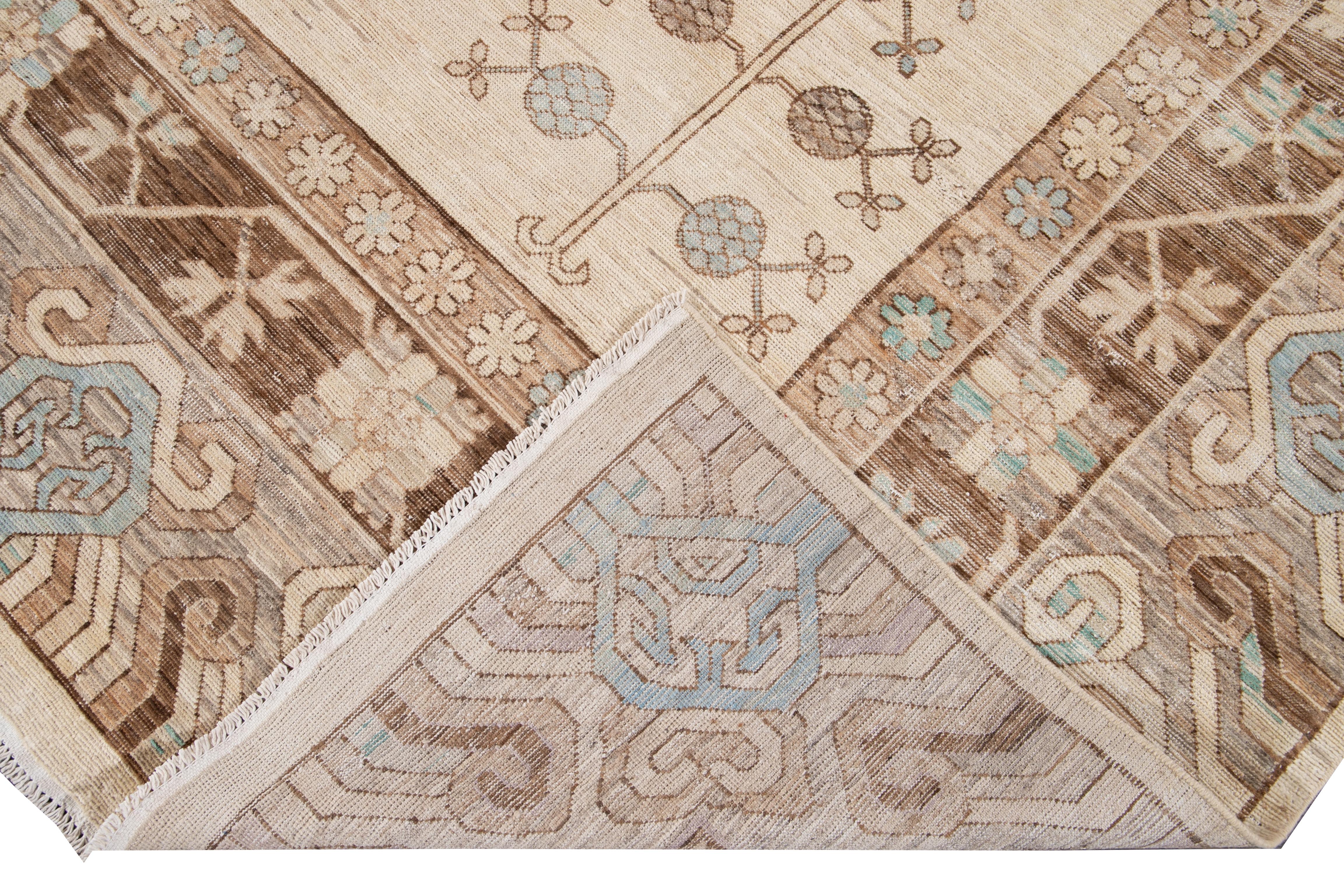 Beautiful modern Khotan style hand knotted wool rug beige field. This Khotan-style rug has a beautifully designed frame and accent of teal, beige, and brown in a gorgeous all-over geometric medallion floral design.

This rug measures 9'10
