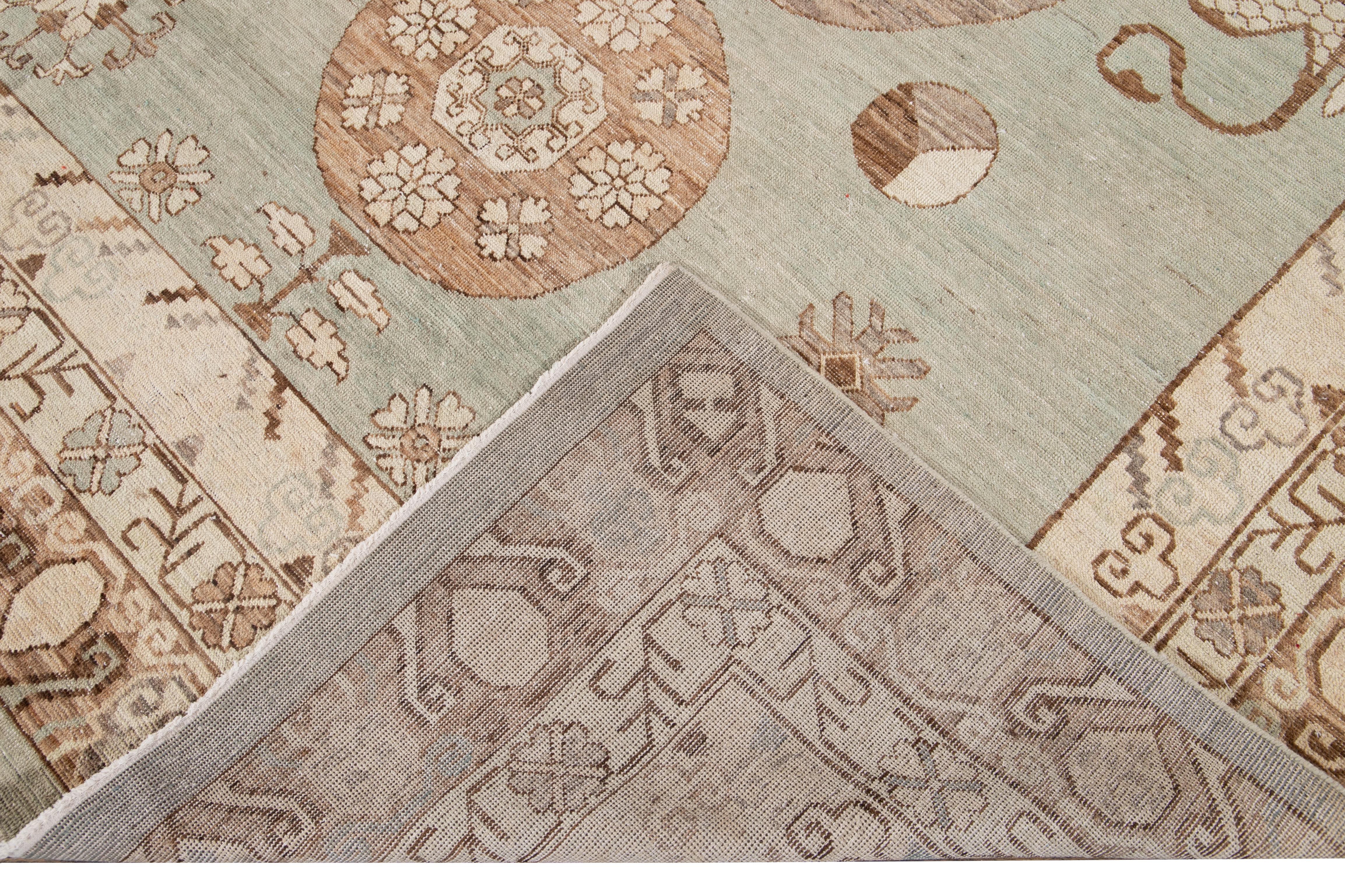 Beautiful Modern Khotan style hand knotted wool rug green field. This Khotan-style rug has a beautifully designed frame and accent of green, beige, and brown in a gorgeous all-over geometric medallion floral design.

This rug measures 7'10