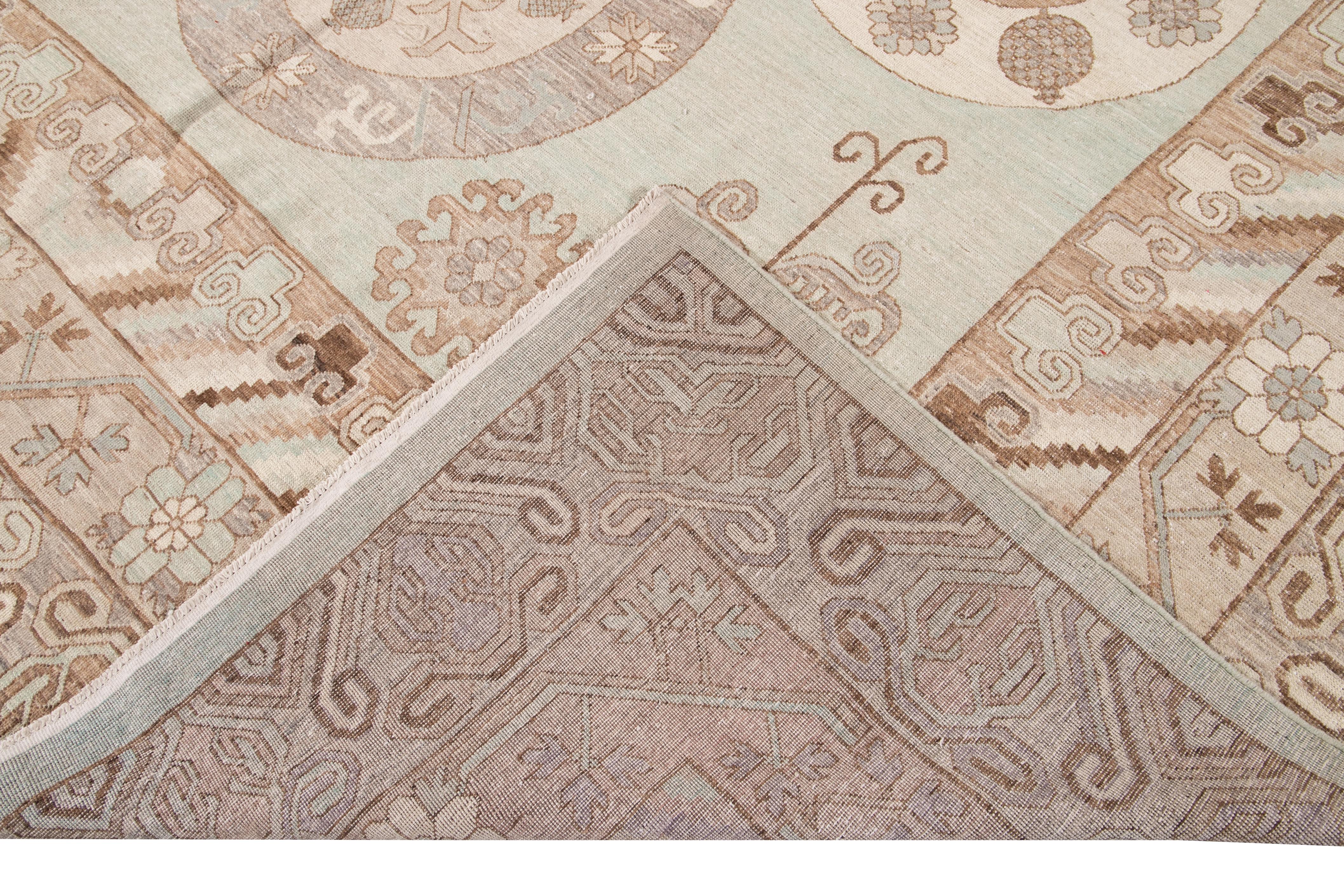 Beautiful modern oversize Khotan style hand knotted wool rug green field. This Khotan-style rug has a beautifully designed frame and accent of blue, beige, and brown in a gorgeous all-over geometric medallion floral design.

This rug measures