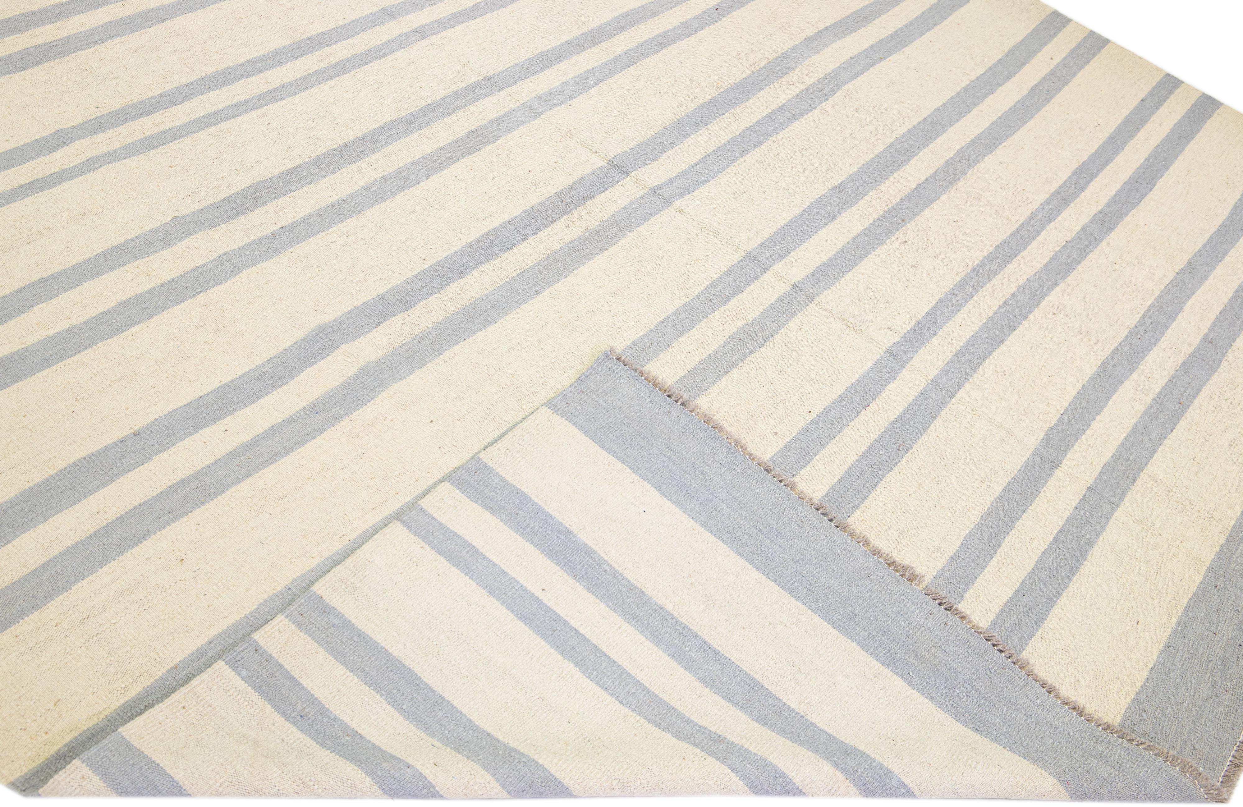 Beautiful Modern flat-weave Kilim handmade wool rug with a beige color field. This Kilim rug has grey accents in a gorgeous stripe design.

This rug measures: 10' x 14'.