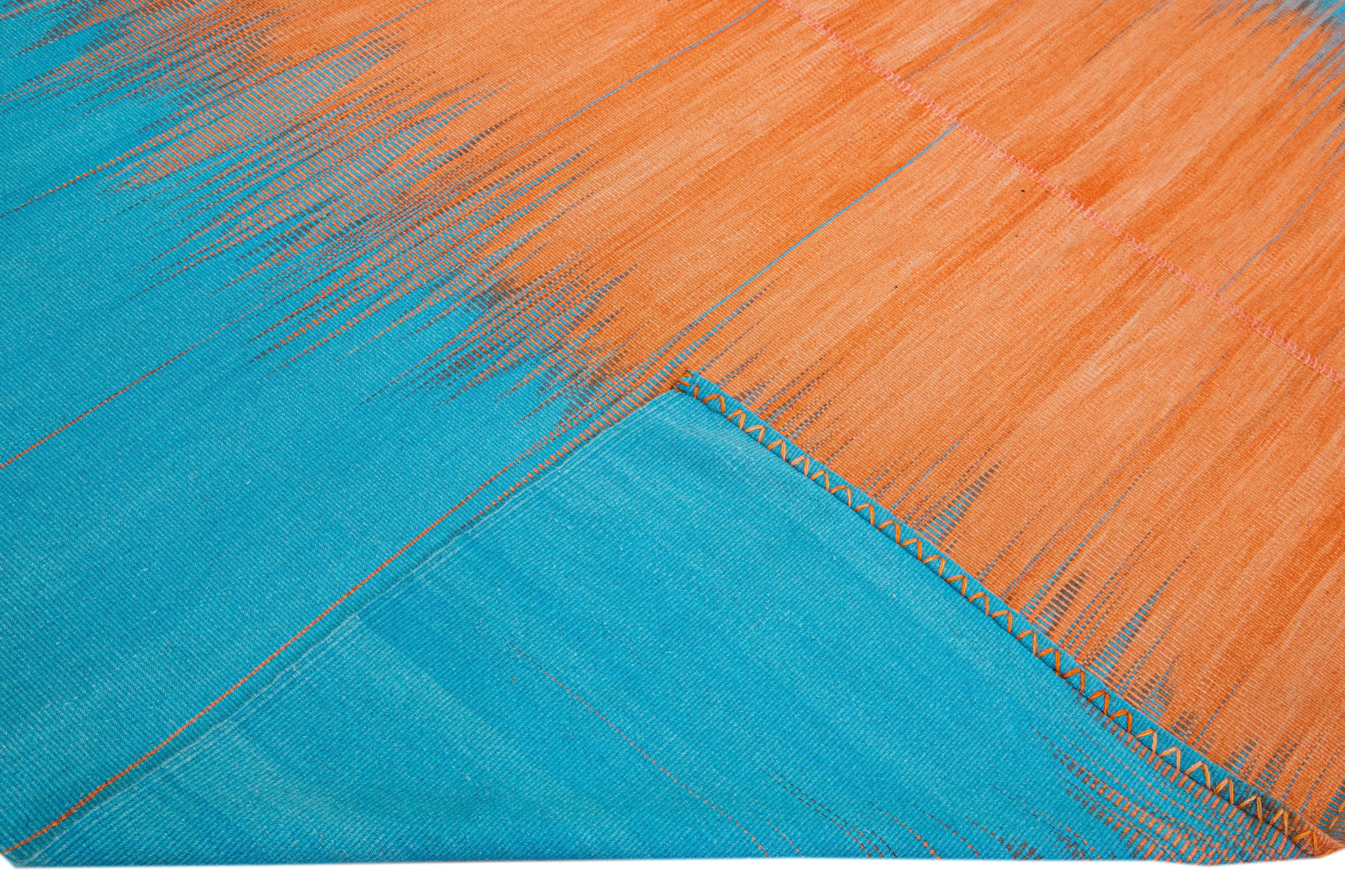 Beautiful modern Kilim flat-weave wool rug with a blue and orange field. This piece of art has a gorgeous abstract retro pattern design.

This rug measures: 9'8