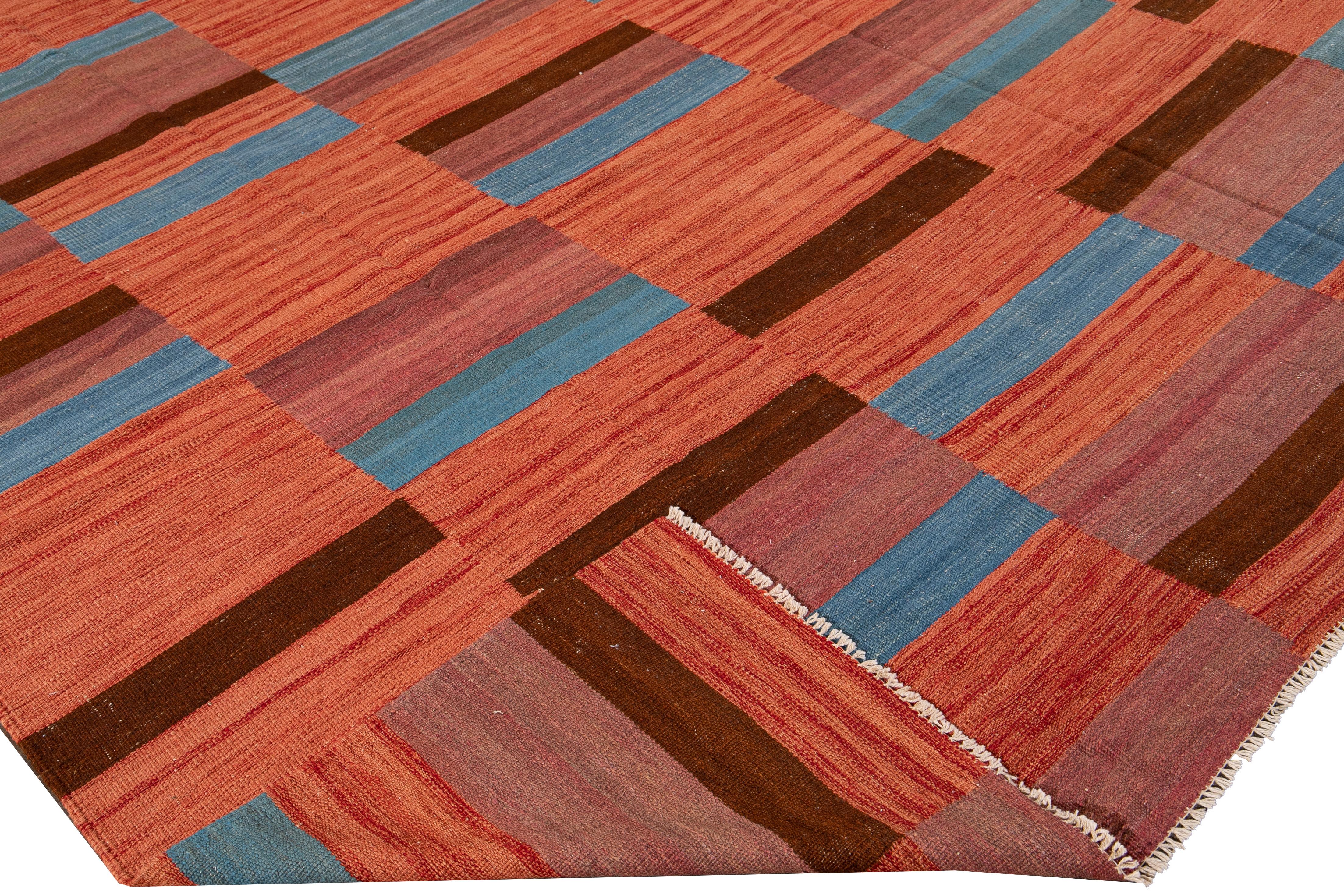 Beautiful modern Kilim flat-weave wool rug with an orange field. This kilim rug has a blue and brown accent in a gorgeous geometric abstract design.

This rug measures: 8'3