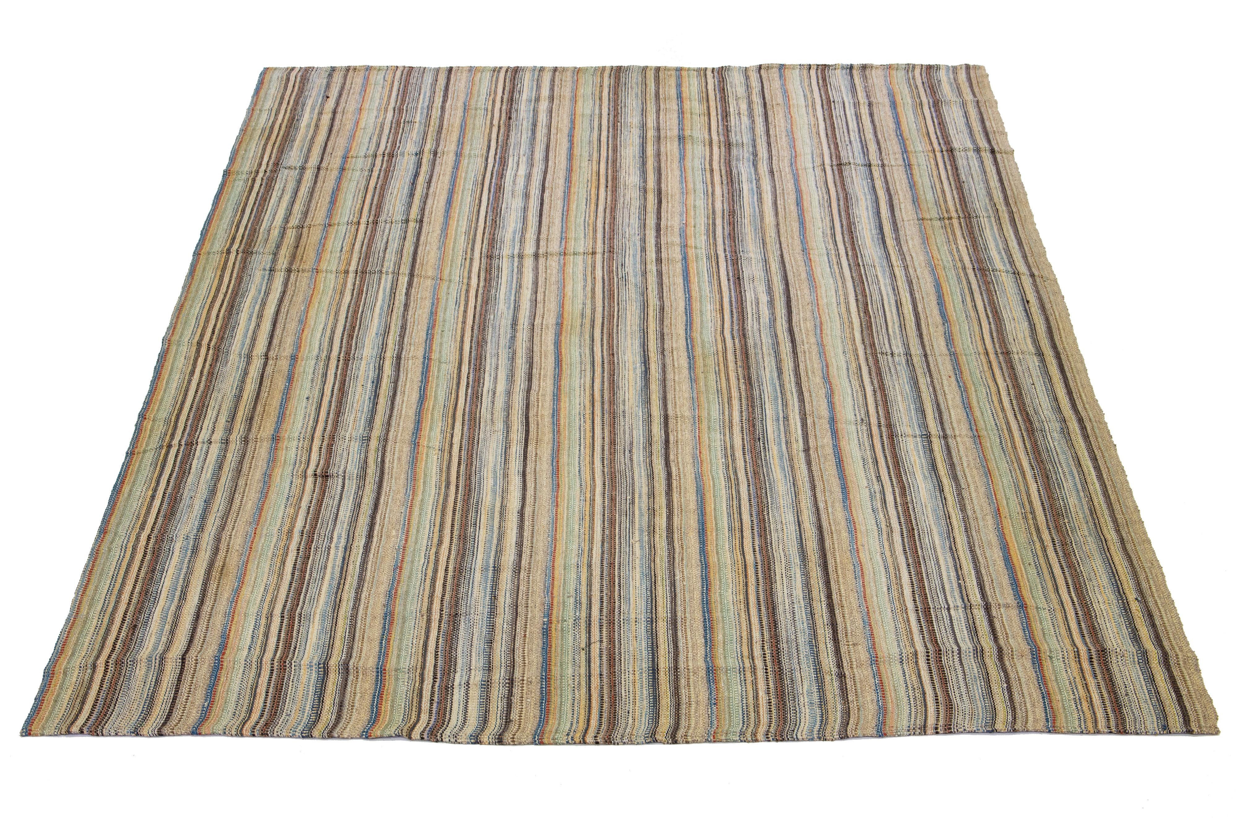 This Indian rug showcases a contemporary Kilim flatweave style crafted from wool. The rug has a beige field with a striped pattern in multicolor shades.

This rug measures 11'6
