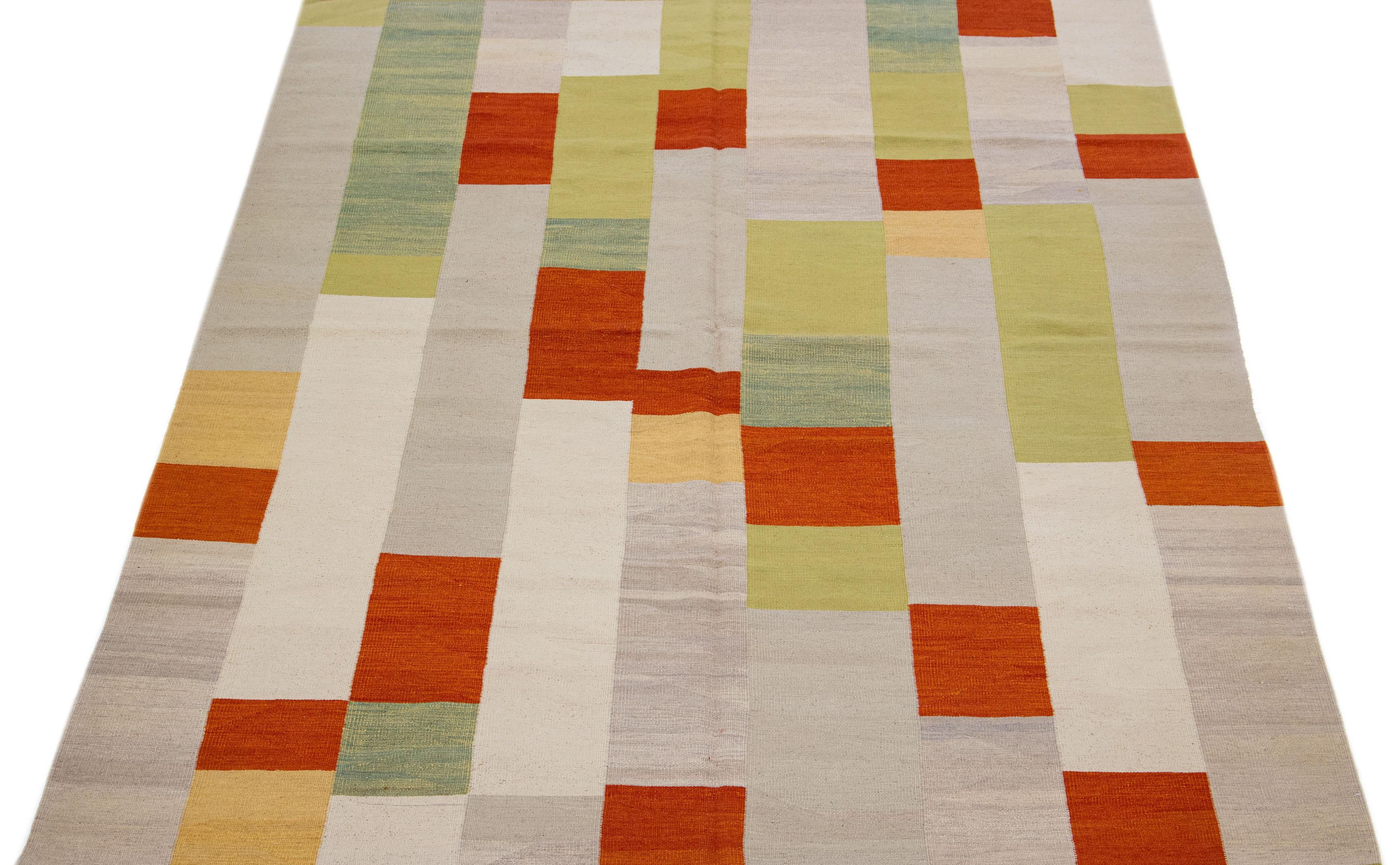 This Indian rug showcases a contemporary Kilim flatweave style crafted from premium wool. Its beige color is complemented by a captivating geometric pattern that blends harmoniously with green and orange hues.

This rug measures 6'6