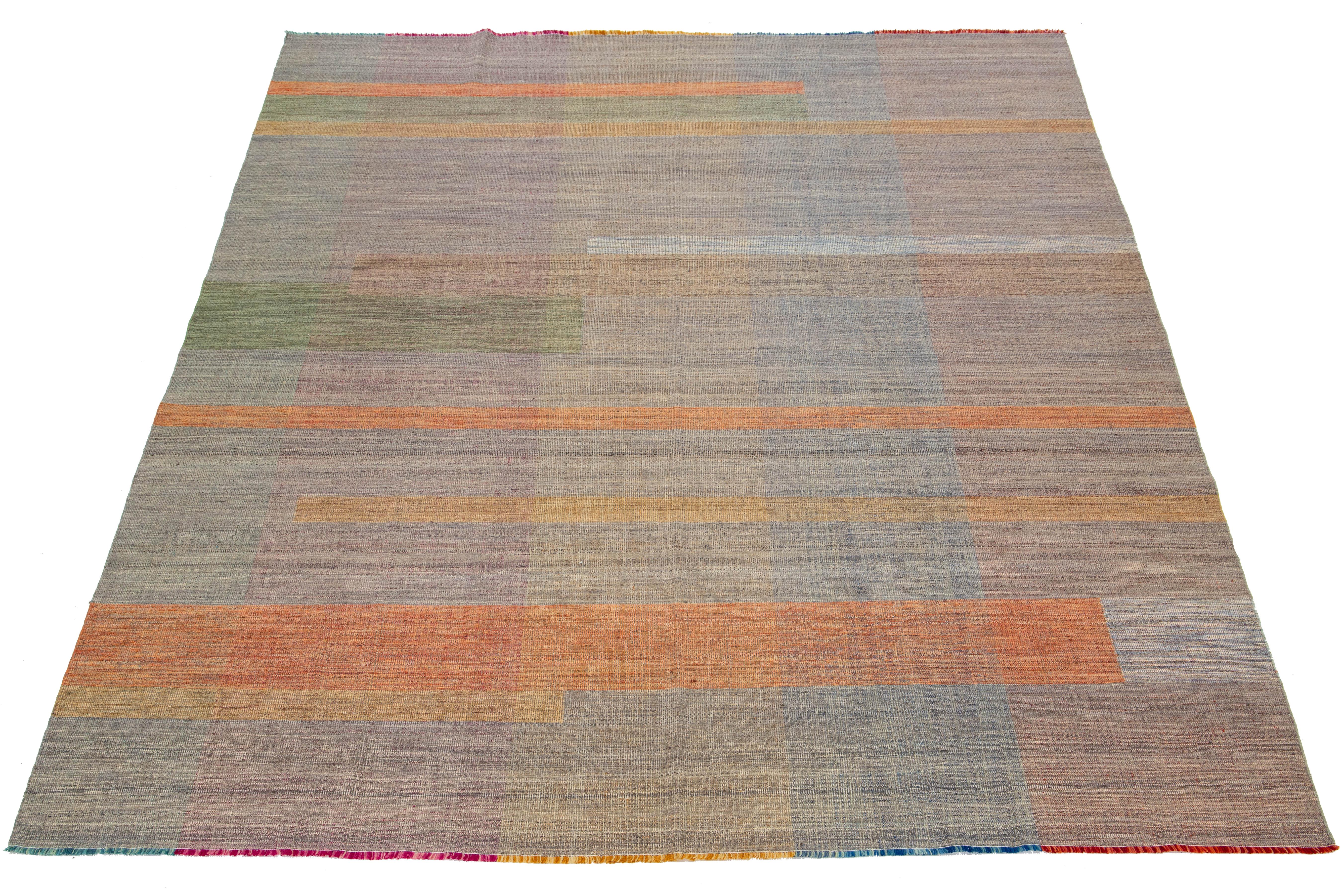 This rug features an organic modern design with a wool Kilim flatweave, showcasing a geometric pattern in vibrant hues of orange, green, and pink.

This rug measures 10'1
