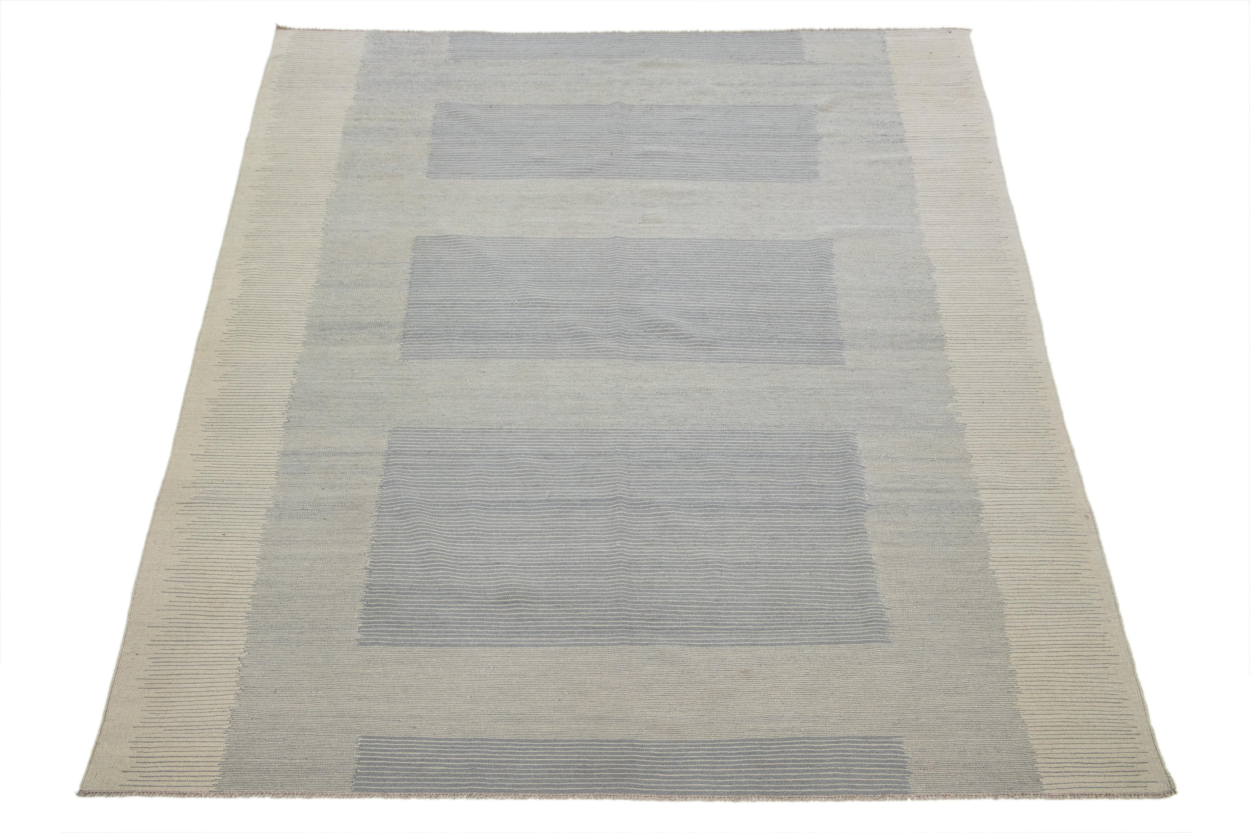 Ein zeitgenössischer Flachgewebe-Kilim-Teppich mit einem beigen Feld, das ein geometrisches Muster in Grau aufweist.

Dieser Teppich misst 8'2