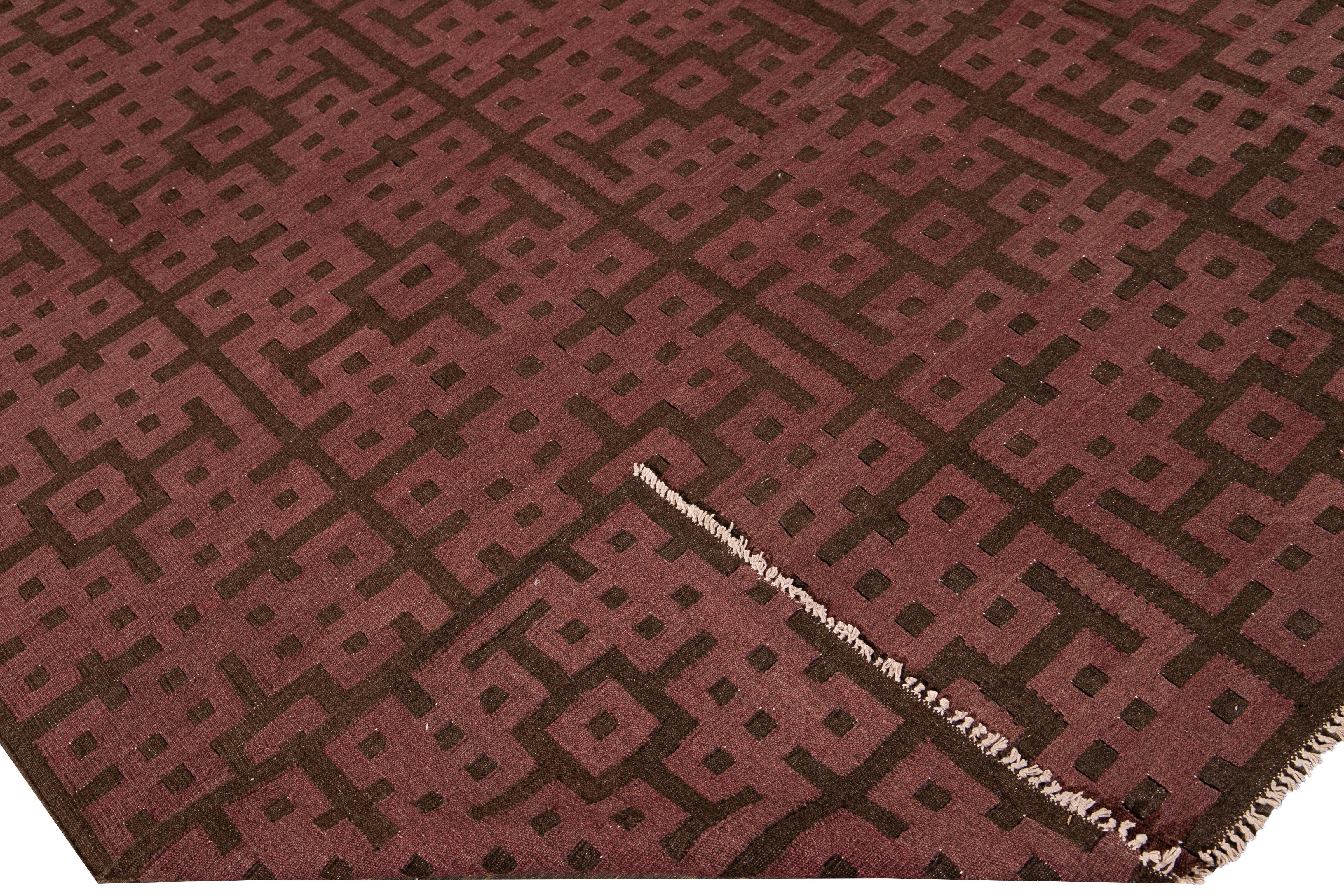 Beautiful modern Kilim flat-weave wool rug with a marron field. This piece of art has brown accents in a gorgeous geometric pattern design.

This rug measures: 9'10