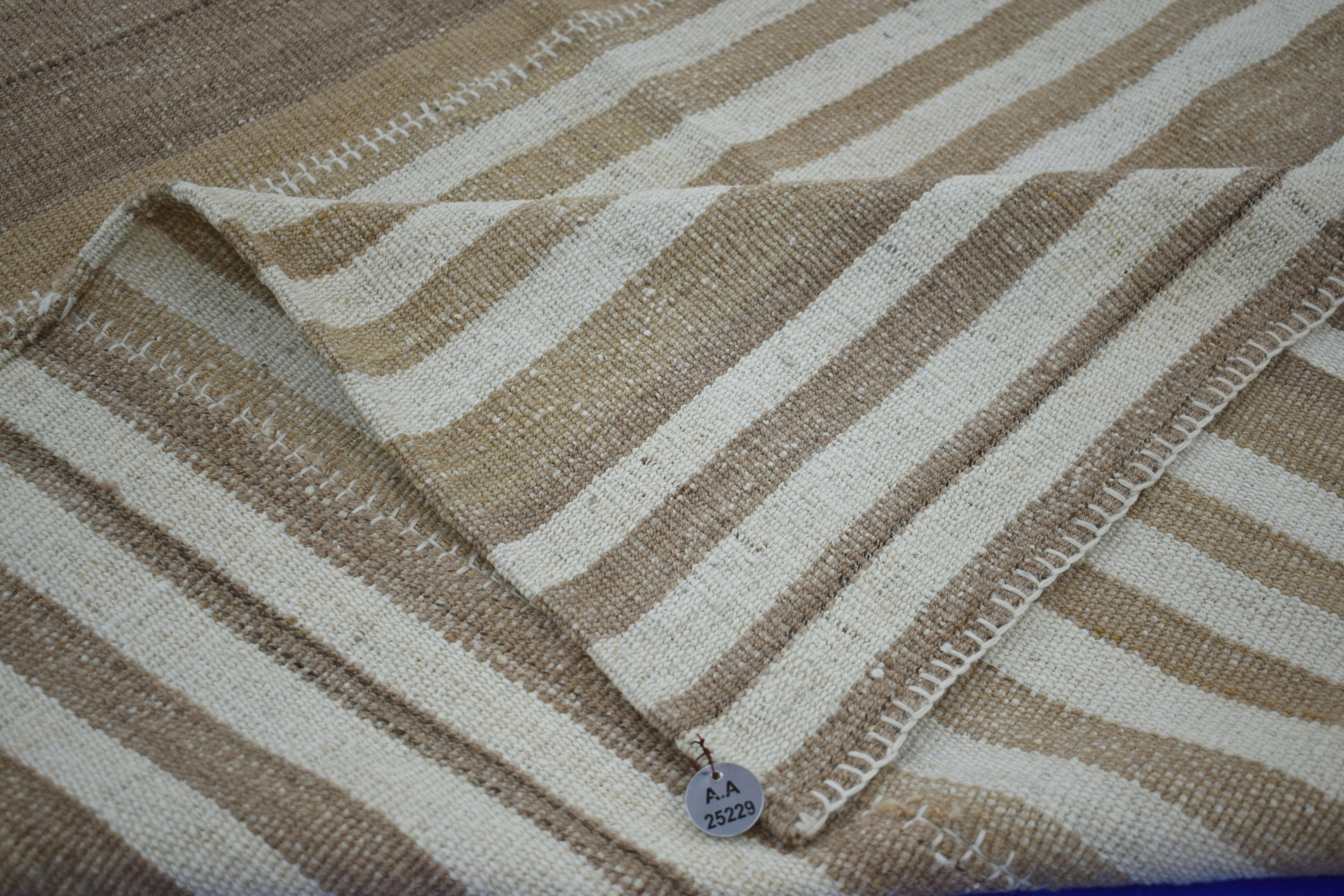  A new production Turkish rug handwoven from the finest sheep’s wool and colored with all-natural vegetable dyes that are safe for humans and pets. It’s a traditional Kilim flat-weave design featuring a striking ivory field of beige and brown