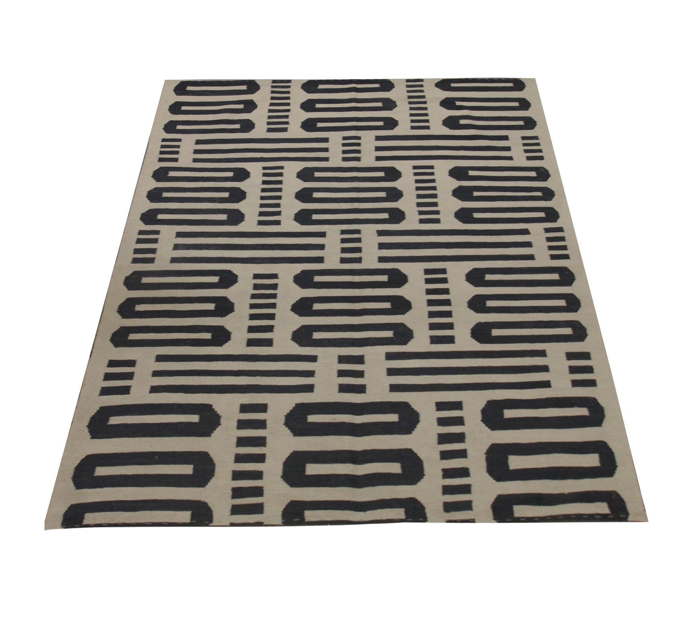 Este atrevido Kilim geométrico es una nueva alfombra moderna tejida a mano en Afganistán. Los motivos de esta pieza cubren toda la cara de esta alfombra con llamativas rayas, puntos y formas ovaladas en una paleta de colores gris y crema en