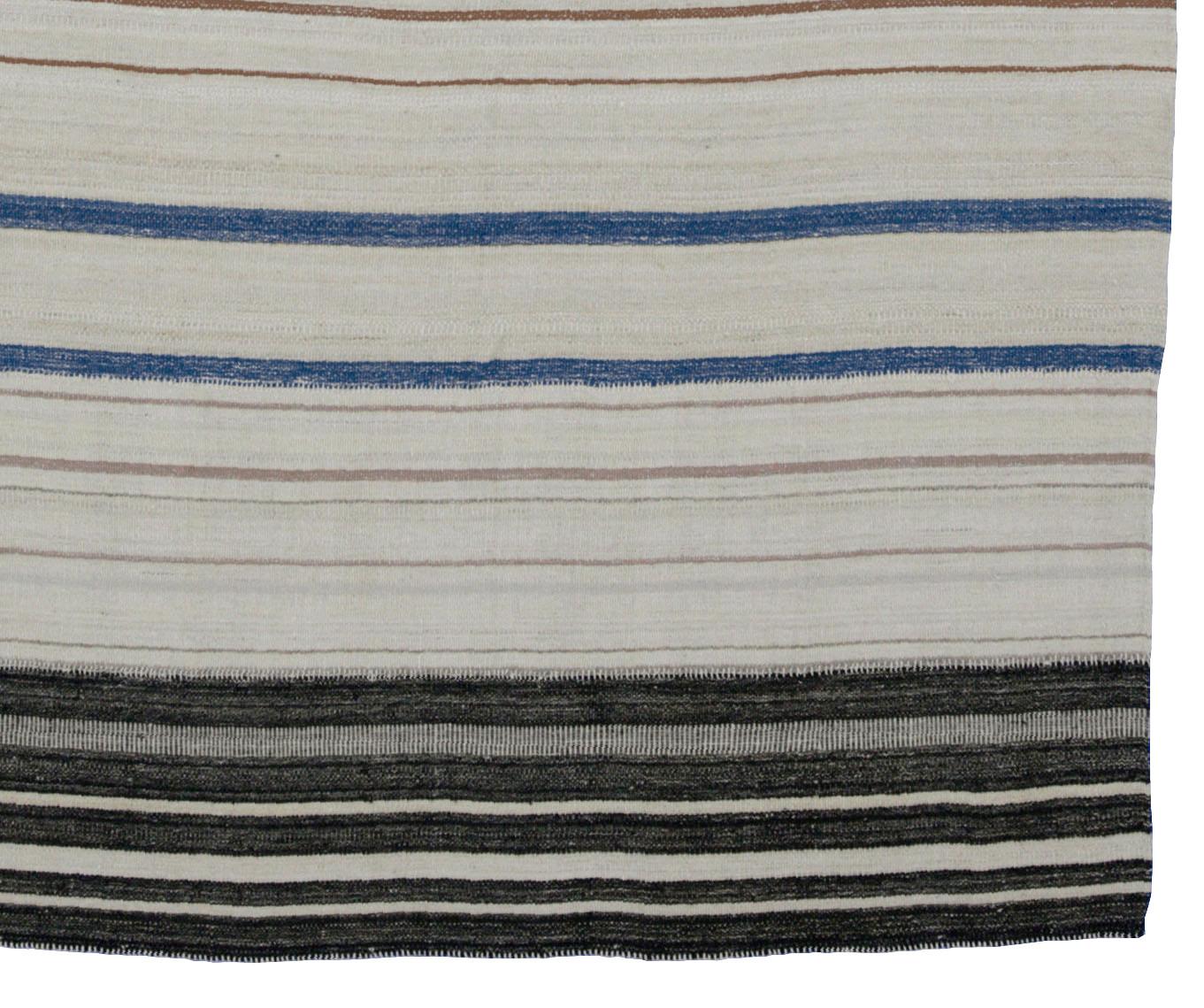 A new production Turkish rug handwoven from the finest sheep’s wool and colored with all-natural vegetable dyes that are safe for humans and pets. It’s a traditional Kilim flat-weave design featuring a lovely ivory field with brown, blue and black