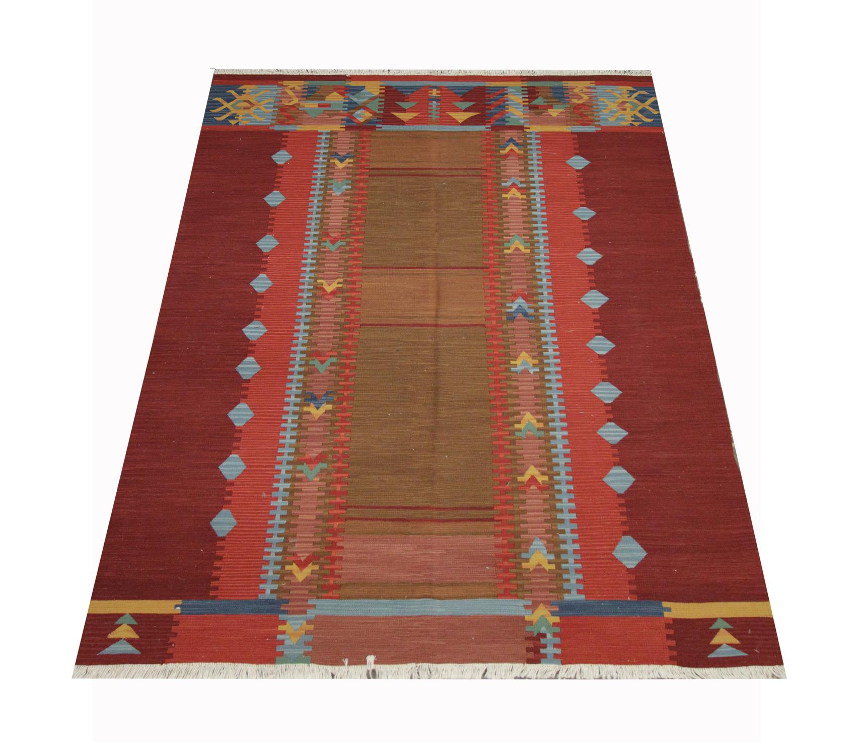 Ce tapis Kilim moderne unique a été tissé à la main au début du 21e siècle en Afghanistan. Les tons terreux et les motifs audacieux révélés dans cette pièce en font le tapis d'accent parfait pour n'importe quel espace. Convient aux espaces