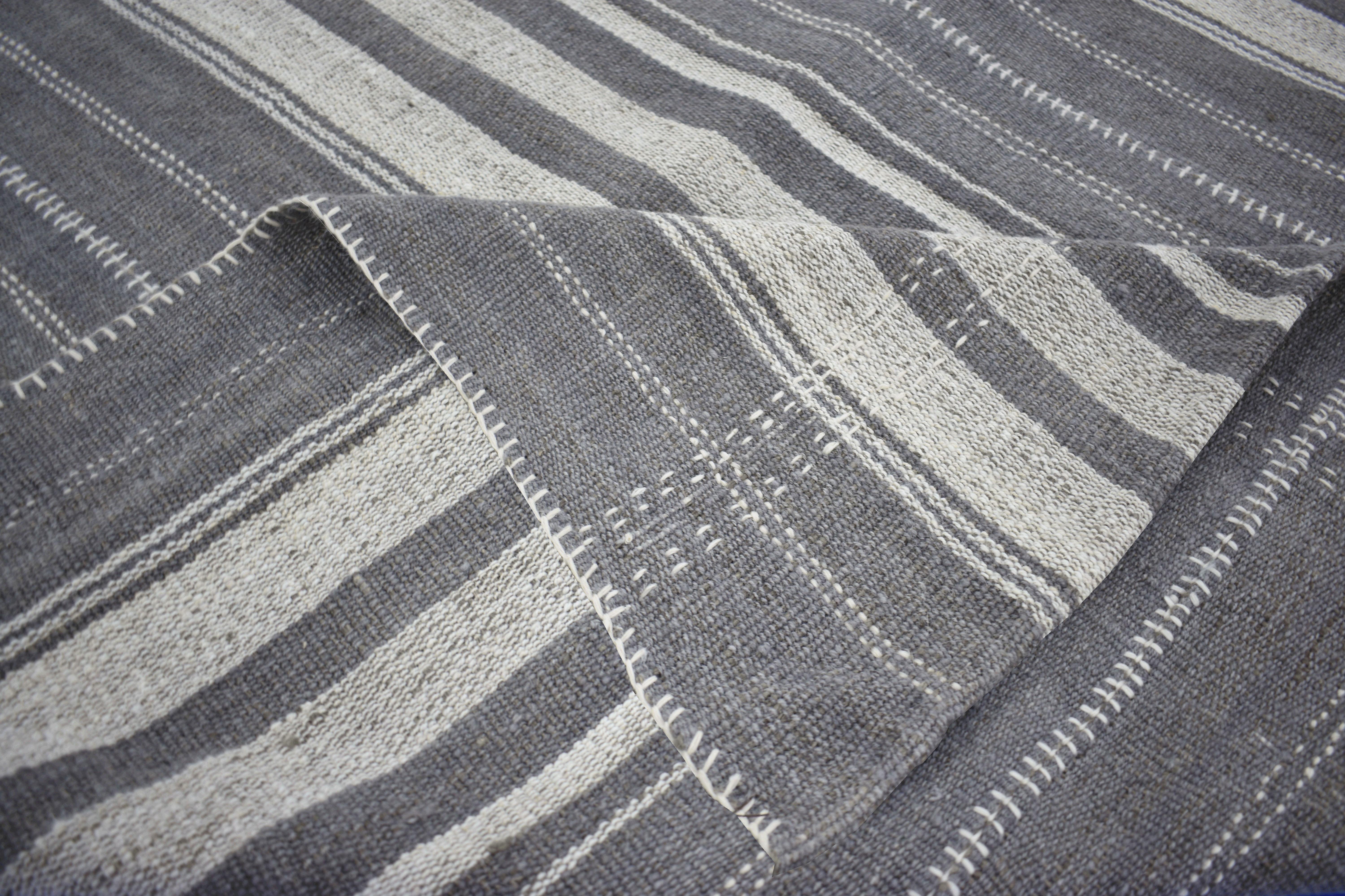 A new production Turkish rug handwoven from the finest sheep’s wool and colored with all-natural vegetable dyes that are safe for humans and pets. It’s a traditional Kilim flat-weave design featuring a lovely ivory field with gray and white stripes.