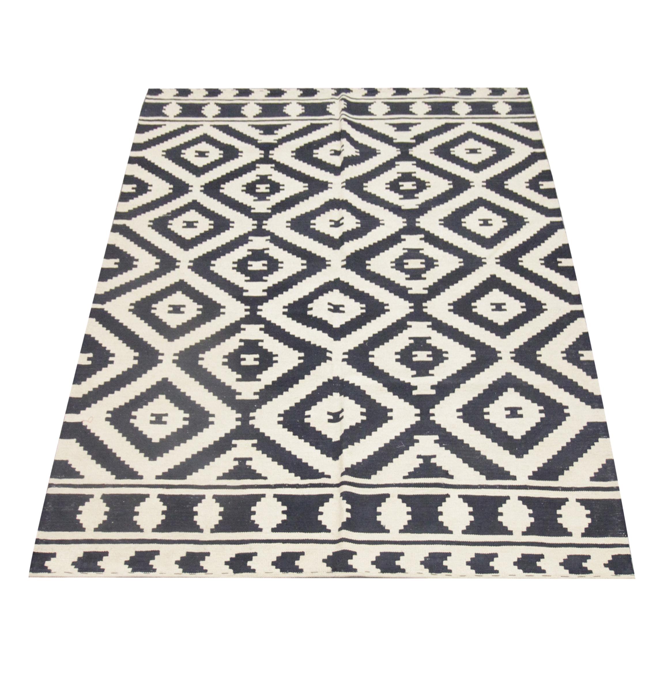 This modern wool rug is a handwoven Kilim constructed in Afghanistan in the early 2000s. The design has been woven with a simple, contrasting colour palette featuring black and cream. The design is a repeating pattern with diamond motifs woven