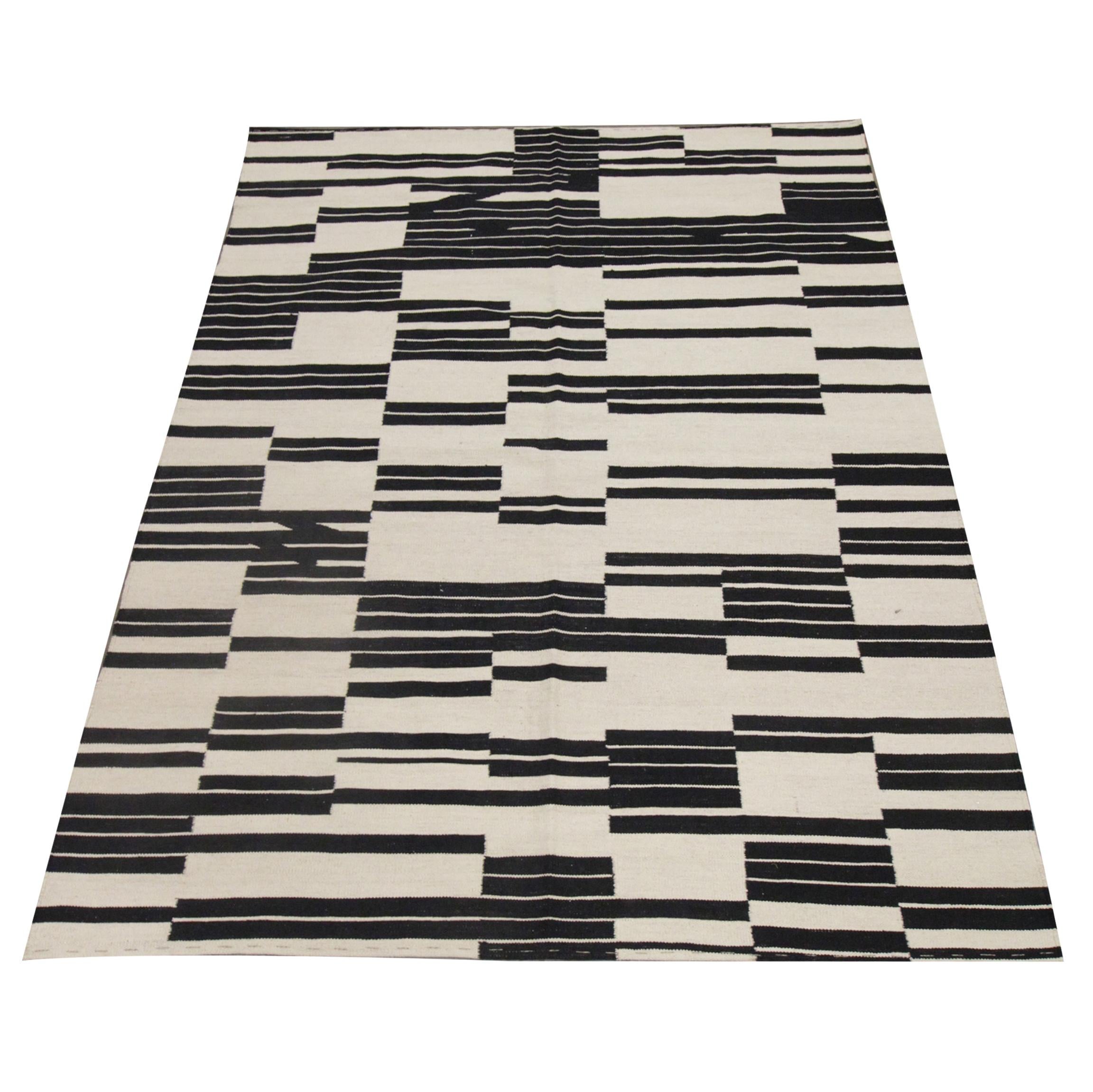 This fine wool Kilim is a modern flat woven area rug constructed in Afghanistan in the early 2000s. The design features an abstract black and white stripe design woven with sophistication. The contrasting colours and bold block design in this piece