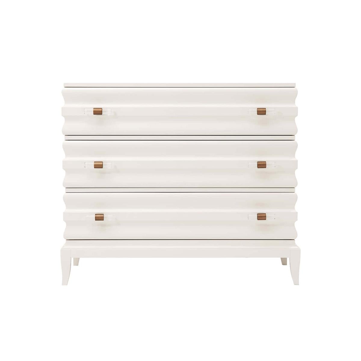 Modern Lacquered Ribbed Commode with a high gloss pearl finish, the rectangular top above ribbed or an ogee molded case and drawers with bronze finish handles clasping optical glass batons, the case raised on splayed saber legs.
Dimensions: 42.5