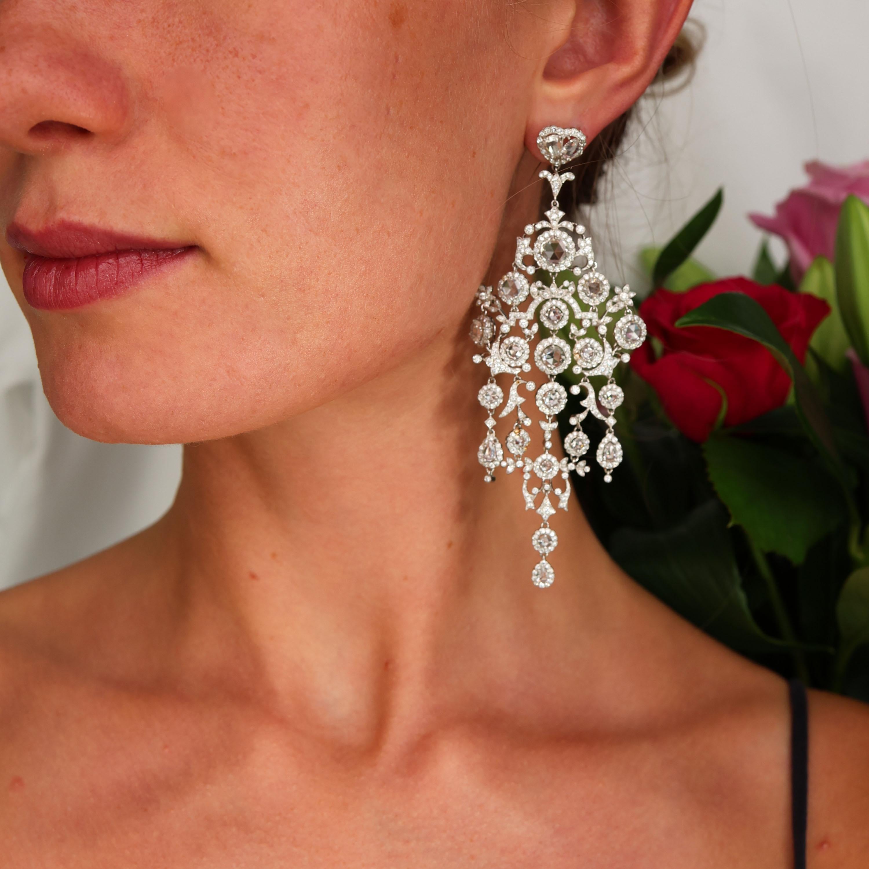 A pair of large chandelier diamond earrings, with clusters of rose-cut diamonds, surrounded by round brilliant-cut diamonds, on an articulating, diamond pave set, openwork frame of scrolls and flowers, with an approximate total diamond weight of