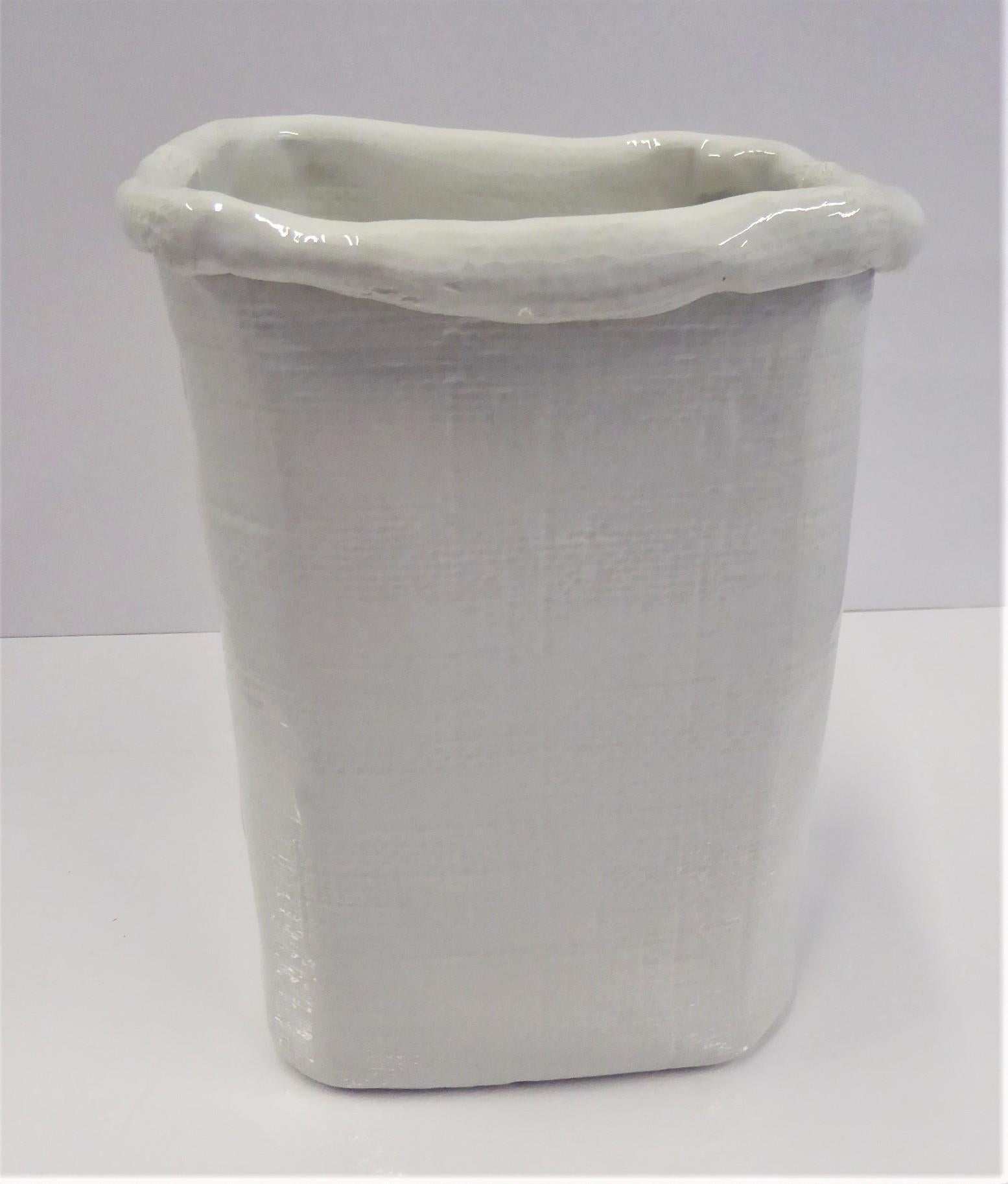 Italian Modern hand made ceramic white vase with a fluid free form shape representing a paper bag. A textured grid design on the outside with folds on the top edge and sides. The bottom incised with Made in ITALY 6494/33.

Measurements: Top- 7 1/2