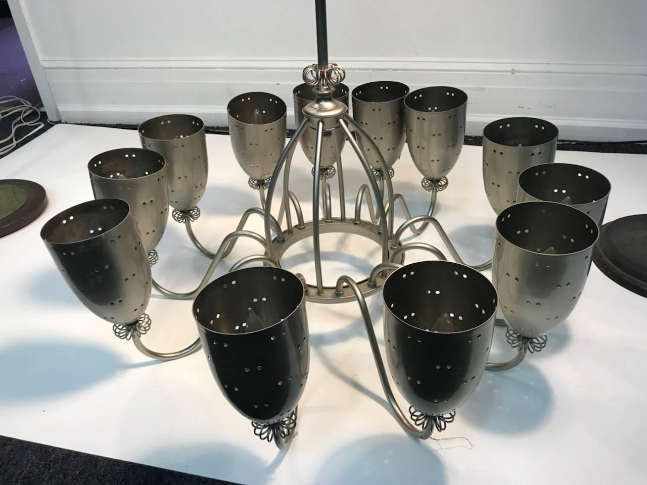 Modern 12 pierced design cup form satin nickel chandelier designed in a midcentury manner with 12 light fixtures. Designed with graceful arms and wire cluster collars and circular form centre.