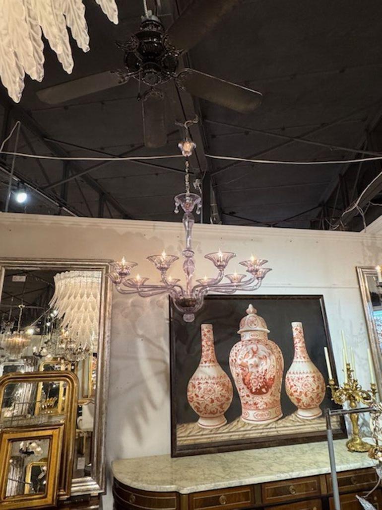 Esta moderna lámpara de araña es de gran tamaño y está fabricada con hermoso cristal de Murano soplado de color lavanda. Con sus 10 brazos, añade un toque elegante a cualquier espacio. Perfecta para quienes buscan añadir un accesorio de iluminación