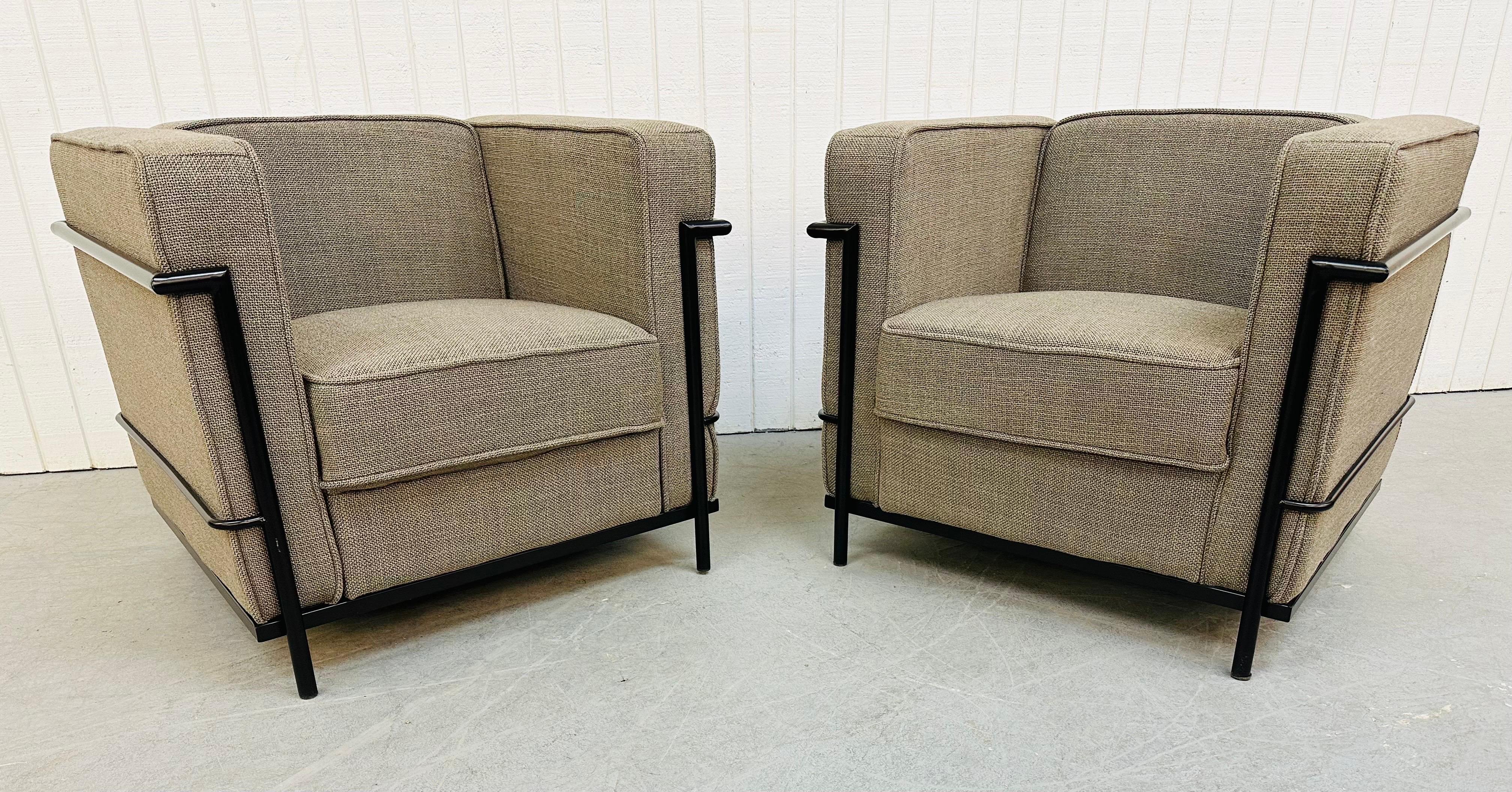 This listing is for a pair of Modern Le Corbusier style club chairs. This iconic reproduction of the LC2 chair features cushions that are upholstered in a gray fabric sitting in a black metal base. These chairs would be a wonderful addition to any