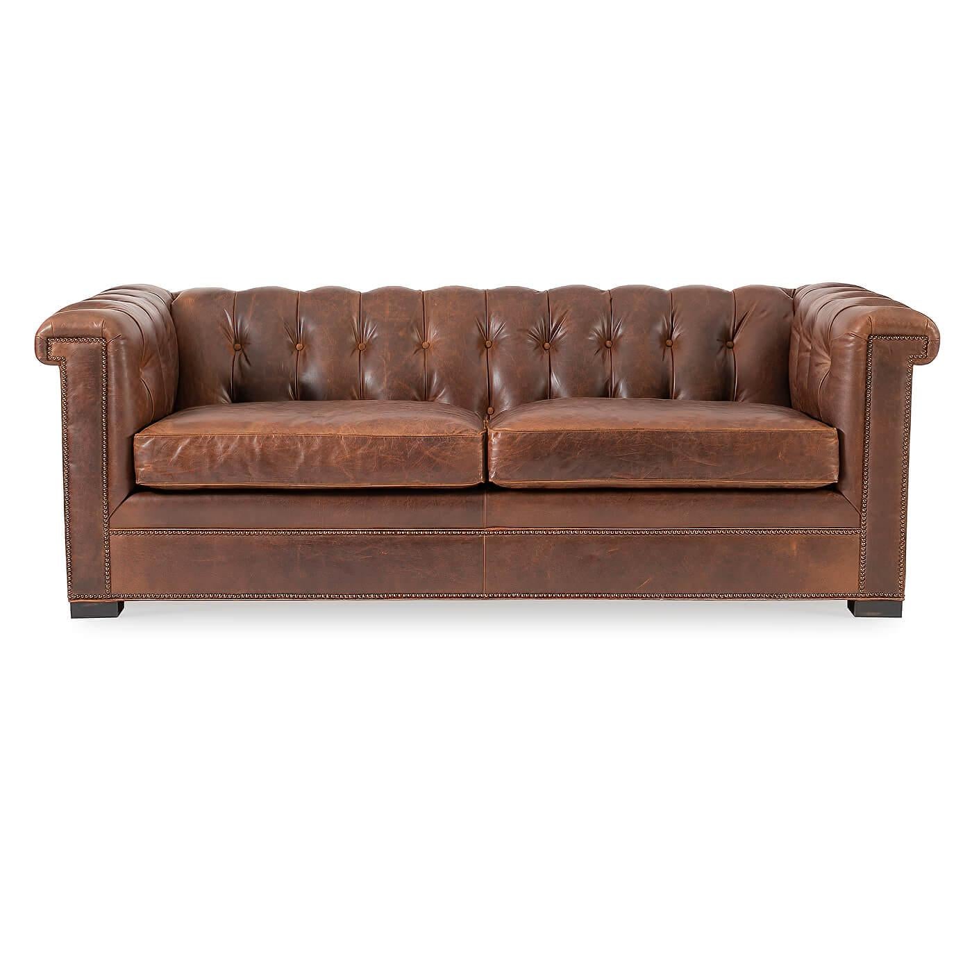 Ein modernes Chesterfield-Sofa aus Leder. Eine Interpretation des traditionellen englischen Designs aus dem 19. Jahrhundert mit quadratischen Armen und Rückenlehne. 

Die Armlehnen und die Rückenlehne sind getuftet und mit zwei bequemen