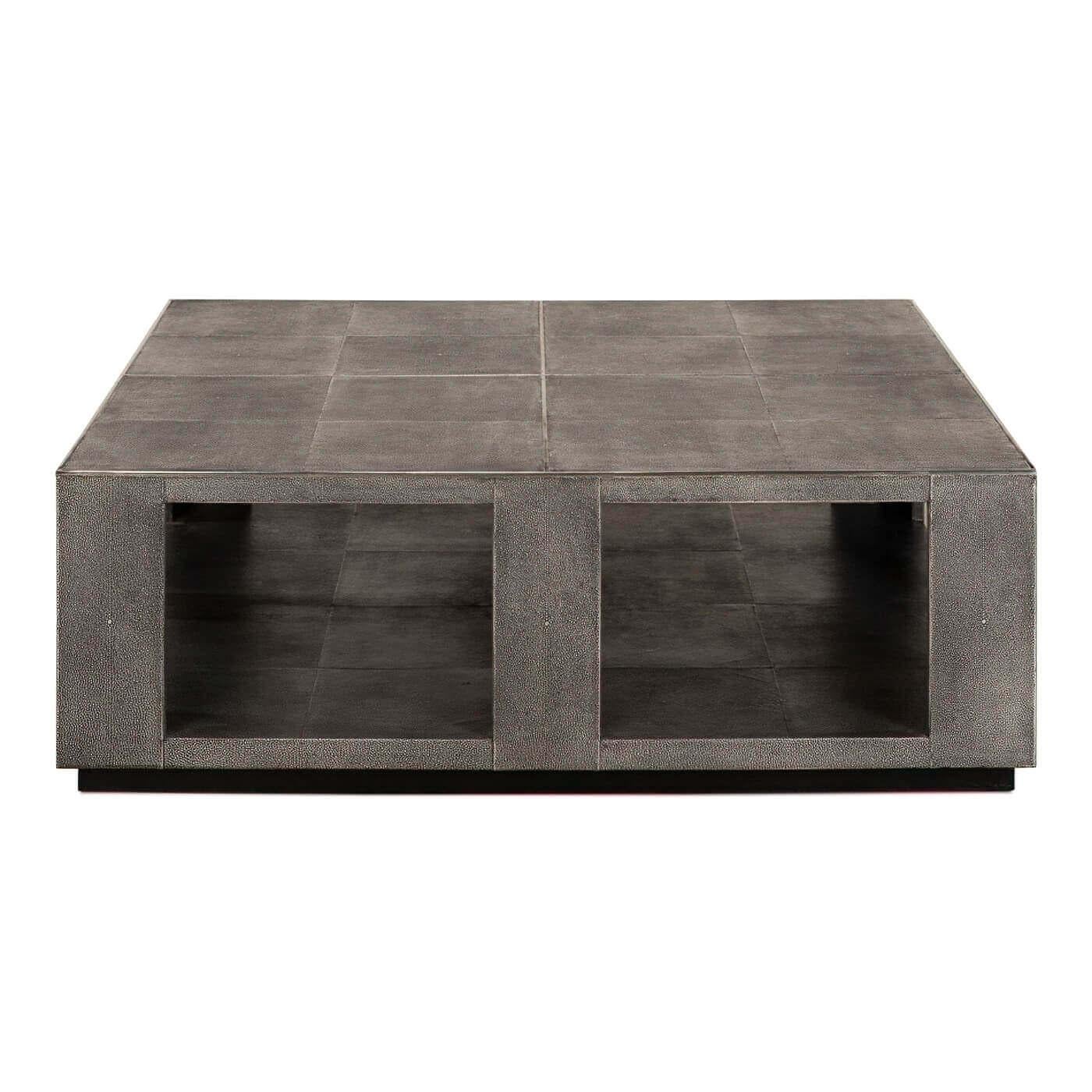 A modern leather square coffee table with stainless steel accents. A sizable coffee table with embossed faux shagreen leather, a lower shelf that is perfect for display and storage. This sleek stylish coffee table rests on a slightly recessed