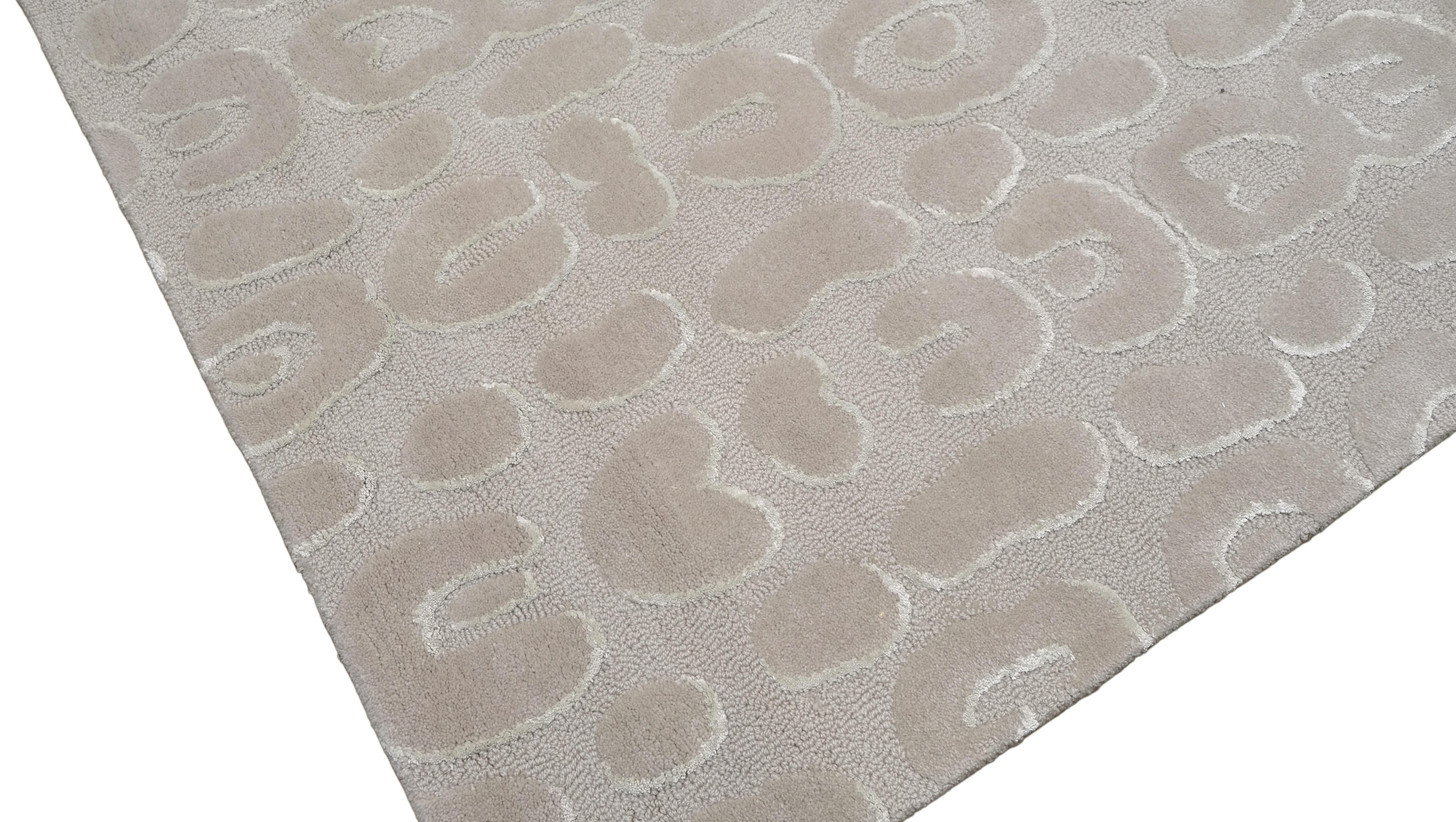 Introduisez une touche de sophistication moderne dans votre espace avec ce tapis en laine tufté à la main, qui présente un motif en relief inspiré des léopards dans des tons doux de gris et de beige. Cette pièce exquise allie une texture élégante à