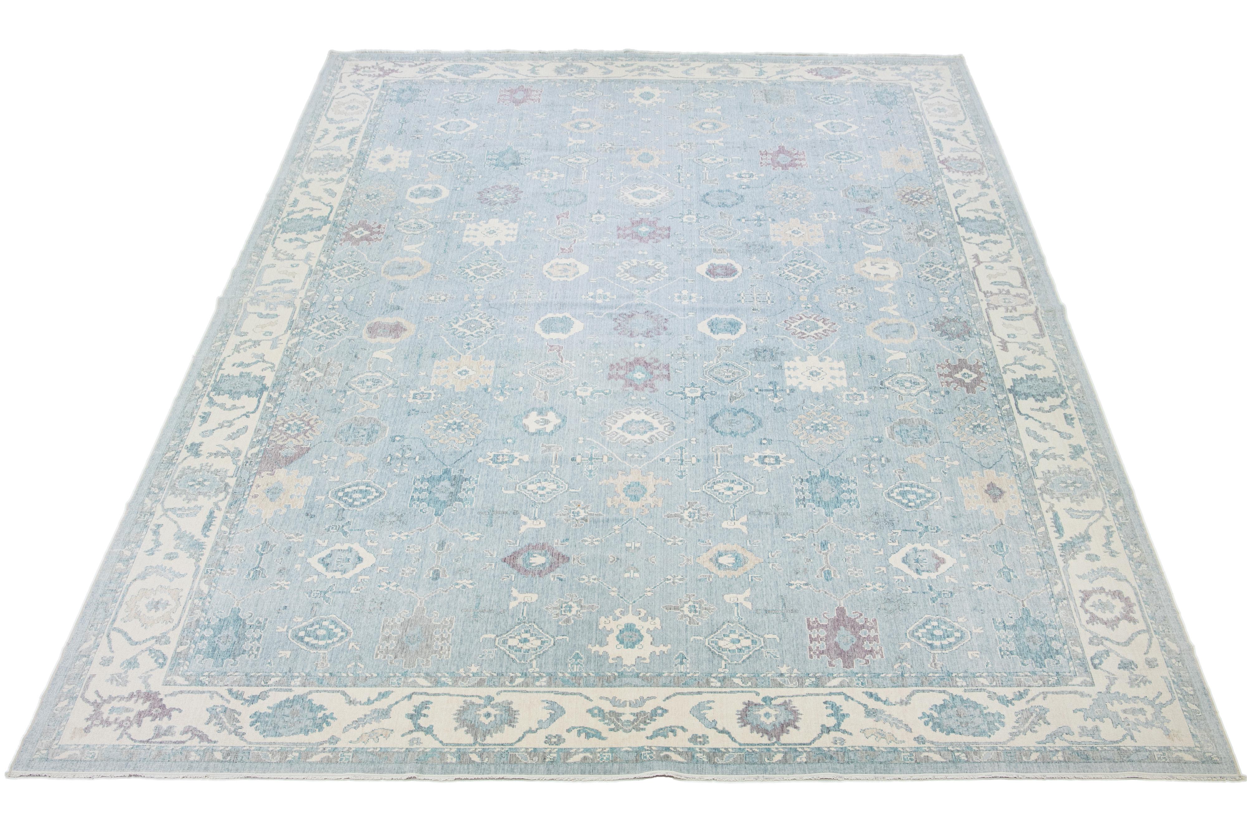 This beautiful, hand-knotted wool rug features a light blue base with a captivating floral pattern in ivory, light brown, and purple accents. It's perfect for complementing any decor.

This rug measures 12'8