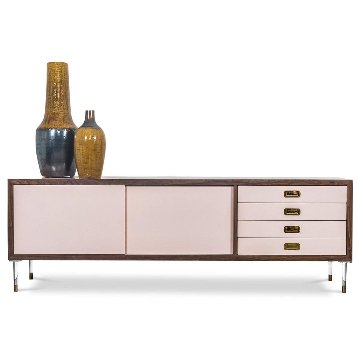 Introducing our new St. Martin credenza featuring two sliding doors and four drawers to maximize its functionality while still being stylish and chic. This retro-modern design features an oiled walnut trim, brass hardware, our famous blush pink