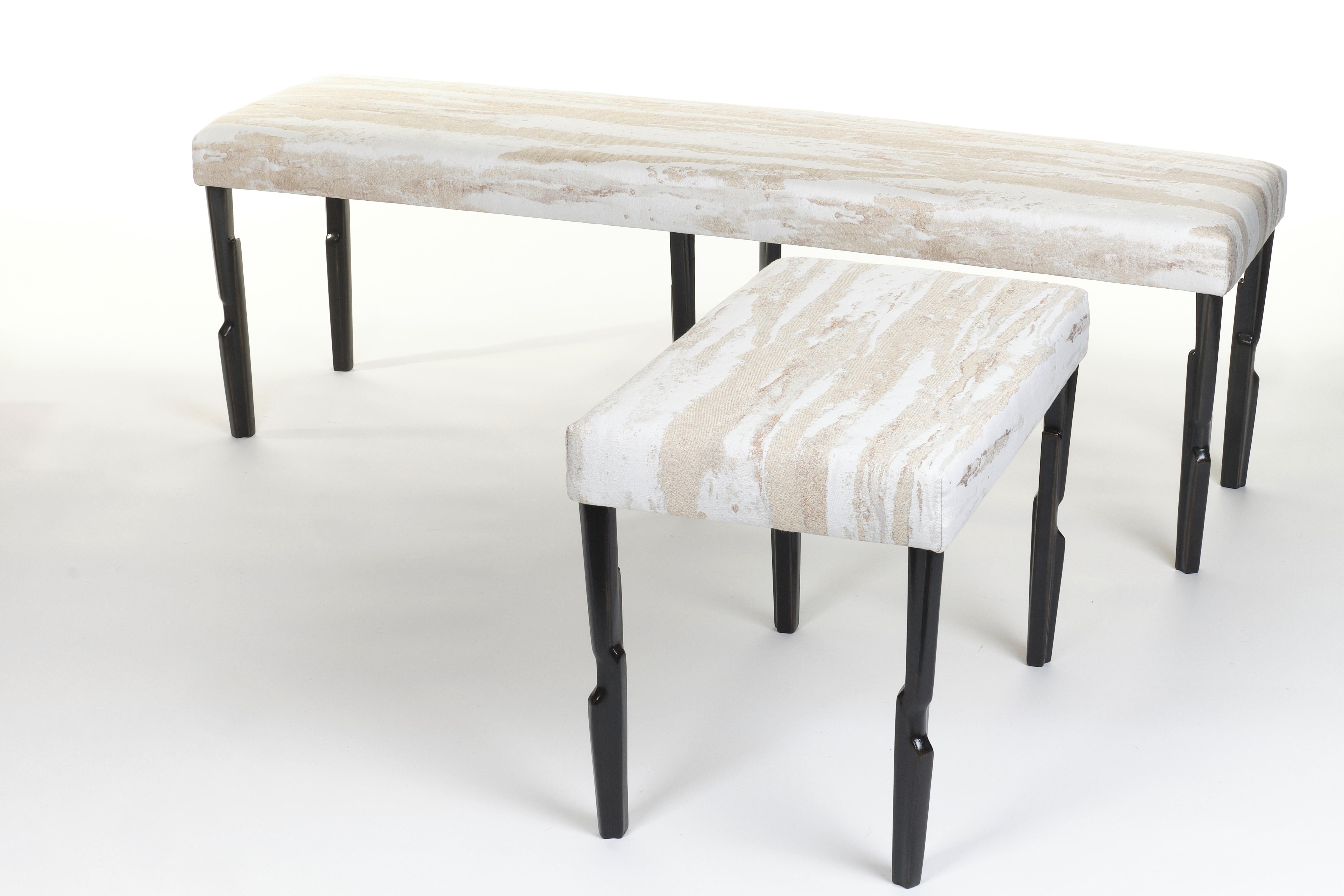Lo sgabello Linea si caratterizza per i suoi piedi artigianali, rifiniti in gesso bronzato, e presenta una seduta imbottita e rivestita in tessuto jacquard della serie 