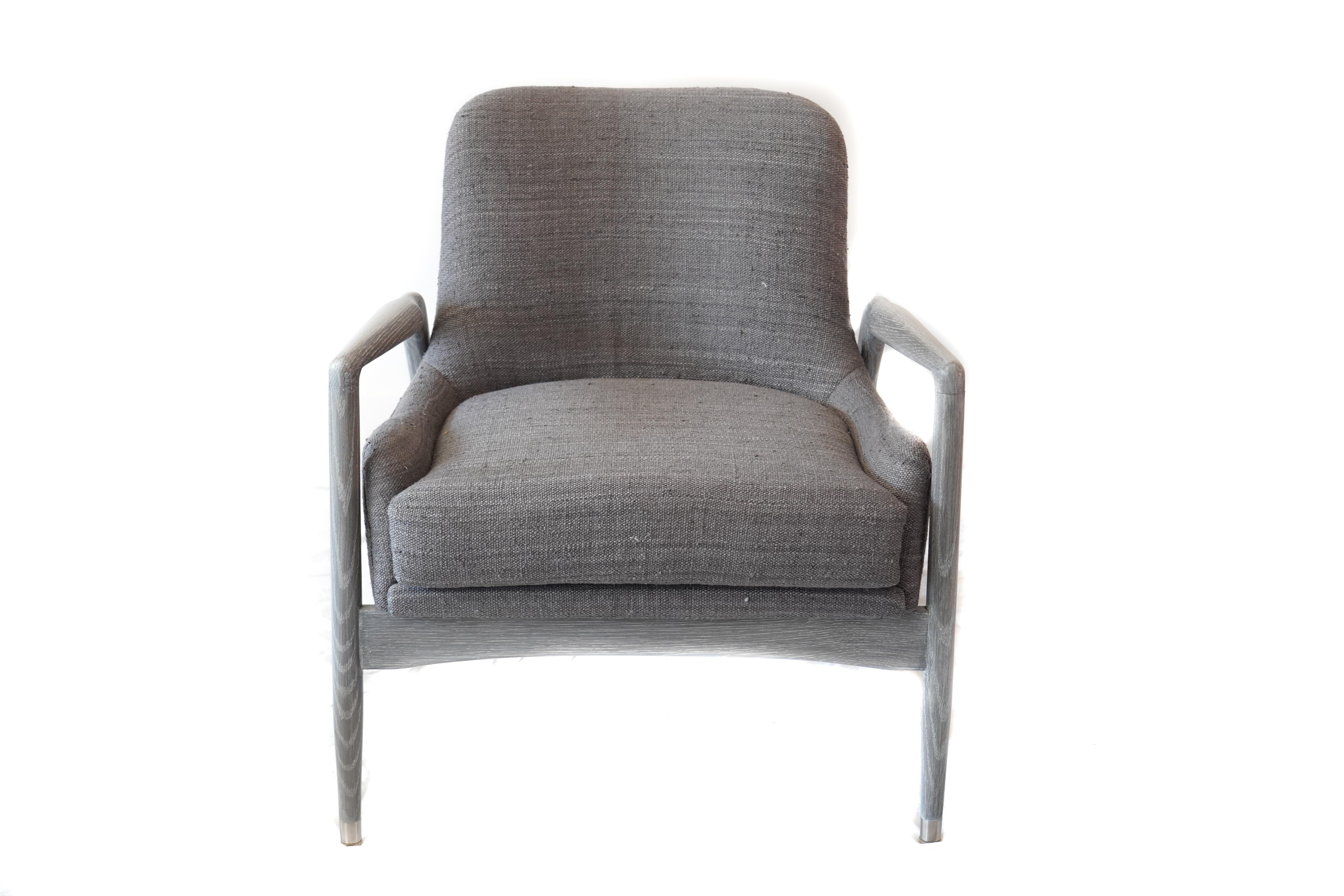 This elegant linen and silk upholstered armchair with a dove grey oak frame evokes clean mid-century lines while providing a comfortable seating experience. The upholstery of the chair provides textured interest and creates a unique visual effect