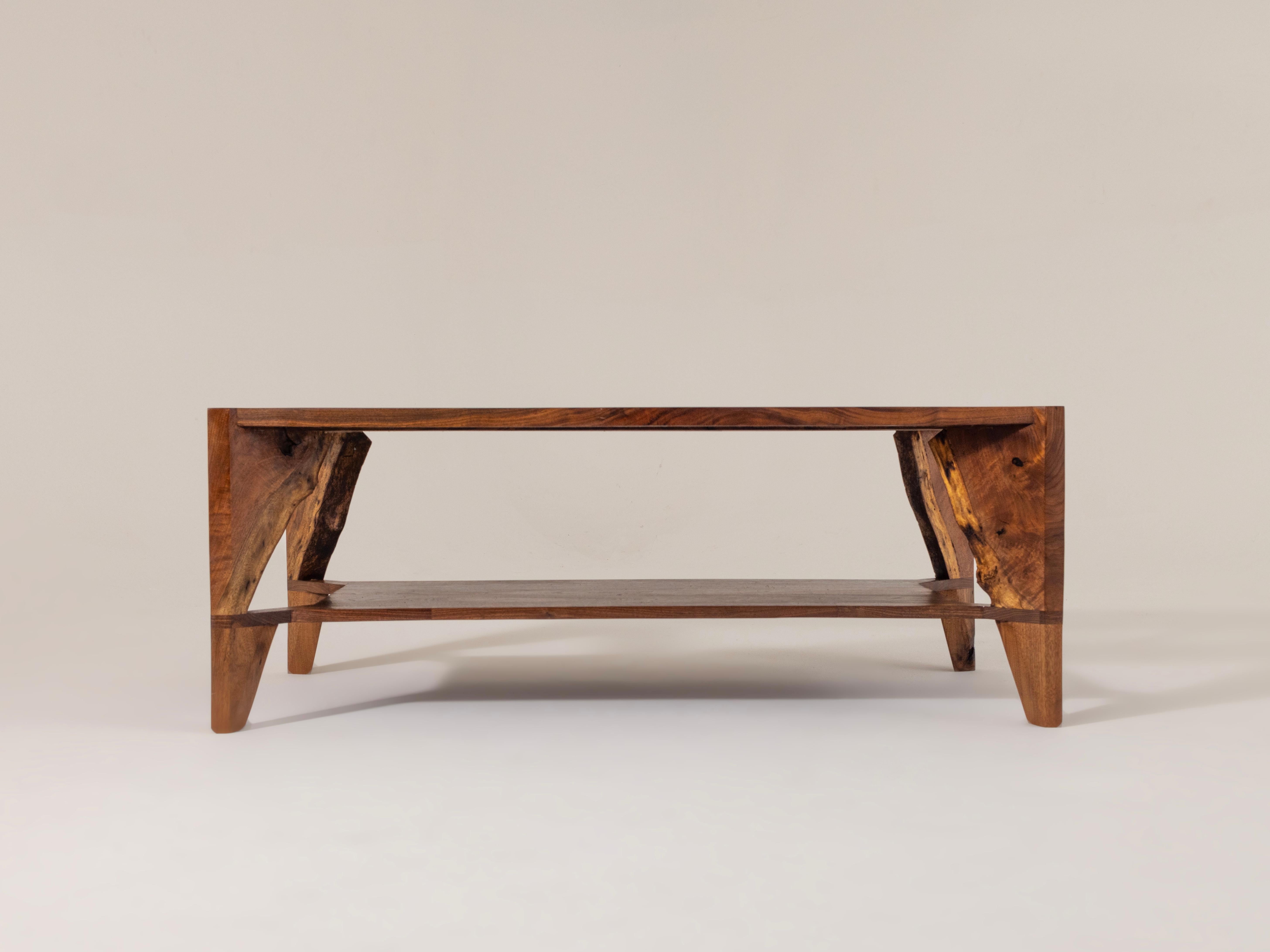 Questo tavolino da caffè artigianale combina una maestria senza tempo con una funzionalità moderna, rendendolo un centrotavola elegante per interni contemporanei e rustici. Il vero noce con bordo vivo mette in mostra le venature naturali del legno e