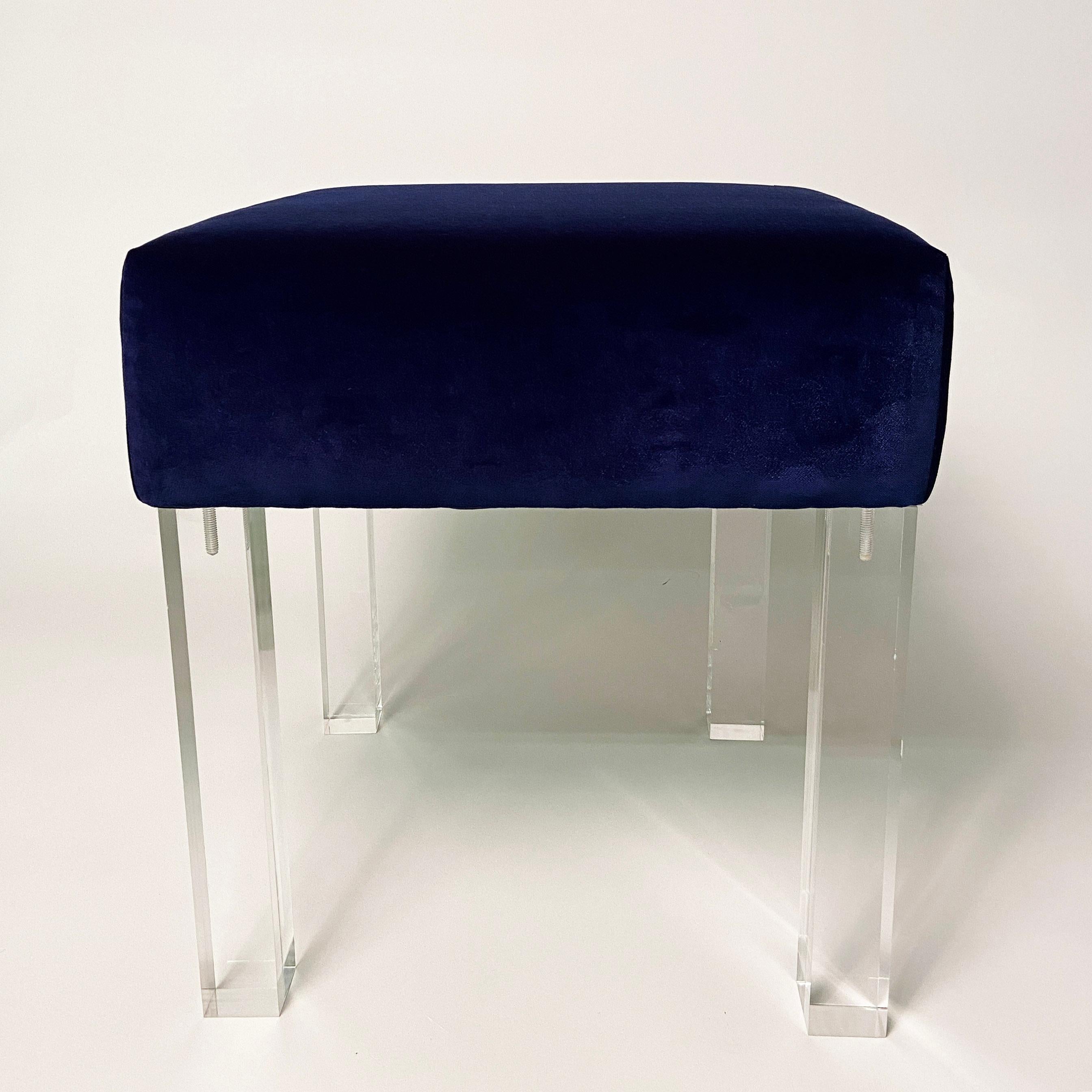 Stunning square low stool with cushion upholstered in fine navy velvet and installed with solid lucite legs. New and in excellent condition. Tuck under a console and pull out for extra seating, place near a fireplace, or at the end of a coffee