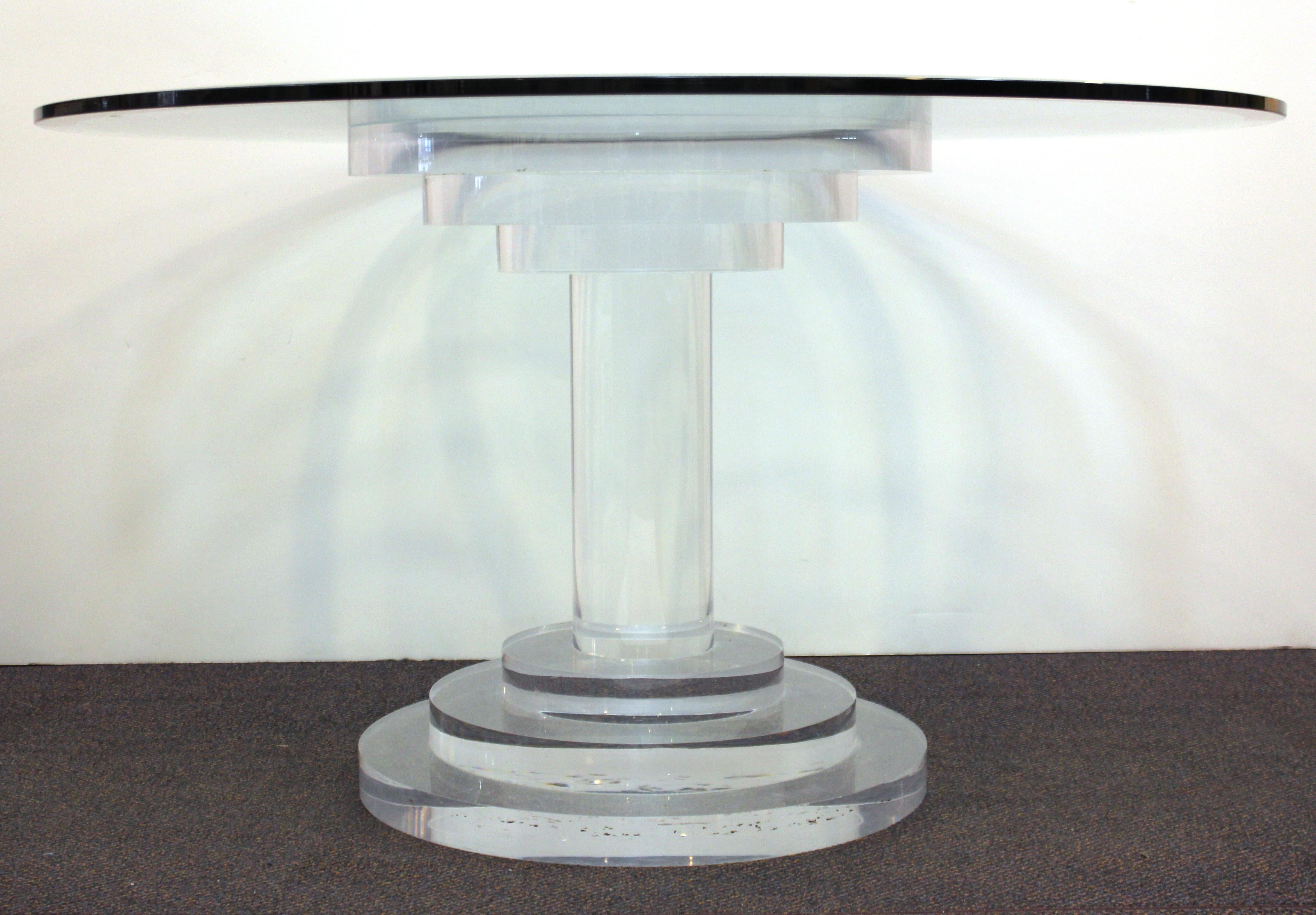 Modern circular dining room table or center table consisting of a heavy glass top on a Lucite base made of stacked concentric cylinders of Lucite. The piece is in great vintage condition with age-appropriate wear.