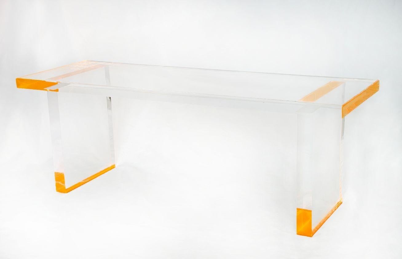 Banc moderne et épuré de Pegaso Gallery Design fait d'une composition de lucite avec des détails orange fluorescents qui ajoutent une explosion de couleurs vives tout en gardant un sens du minimalisme grâce à son design épuré. Fabriqué aux