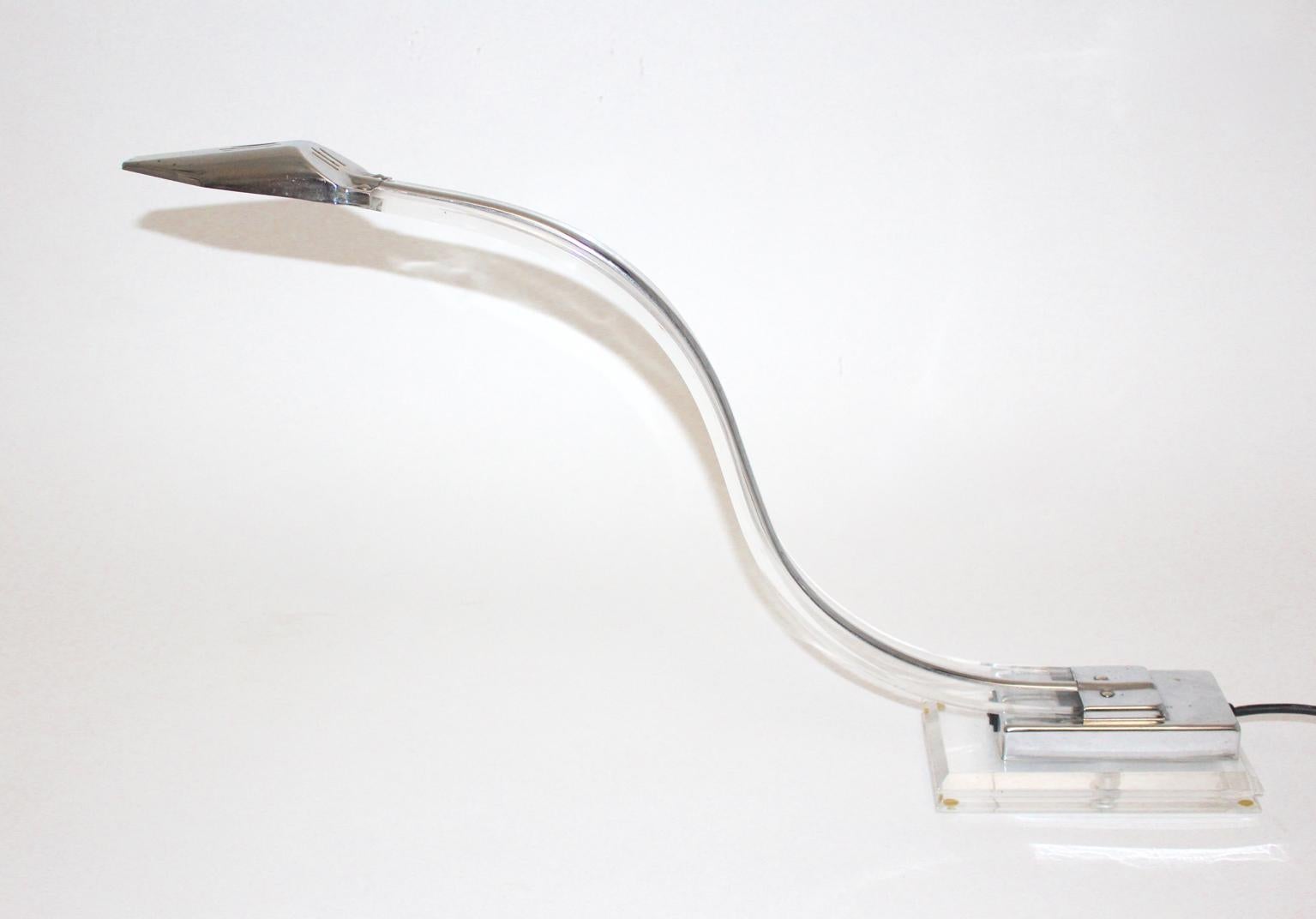 This table lamp was designed and made in the 1980s. So the table lamp shows a curved Lucite arm and a chromed details at the base and at the shade.
Furthermore the desk lamp features a two step switch and shows a socket for halogen bulbs.
The