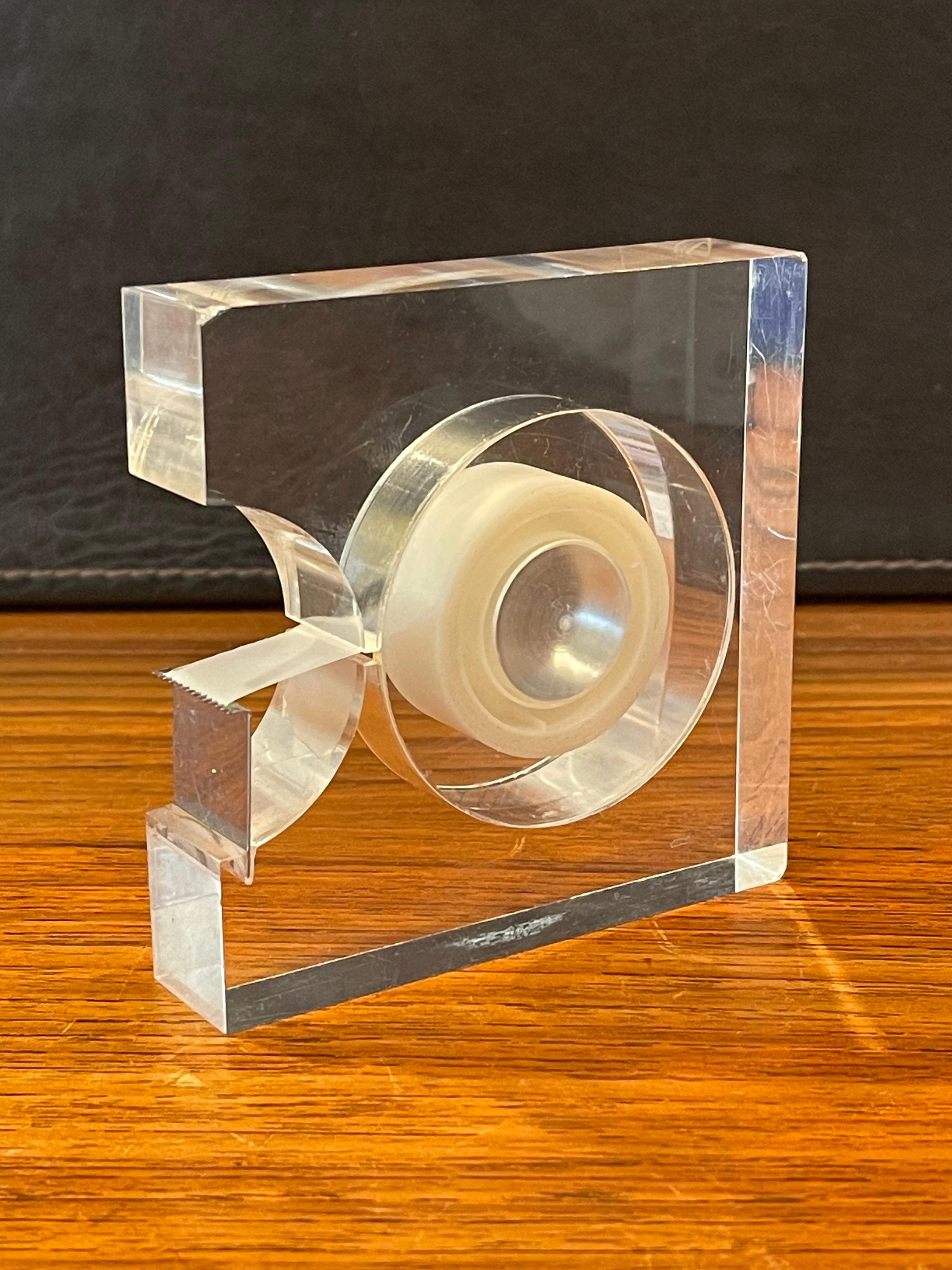 Very functional modern lucite tape dispenser by Two's Company of New York for the Design Study Collection of the Museum of Modern Art (MoMA), circa 1970s. The piece is in very good condition (no crazing or discoloration) with the exception of two