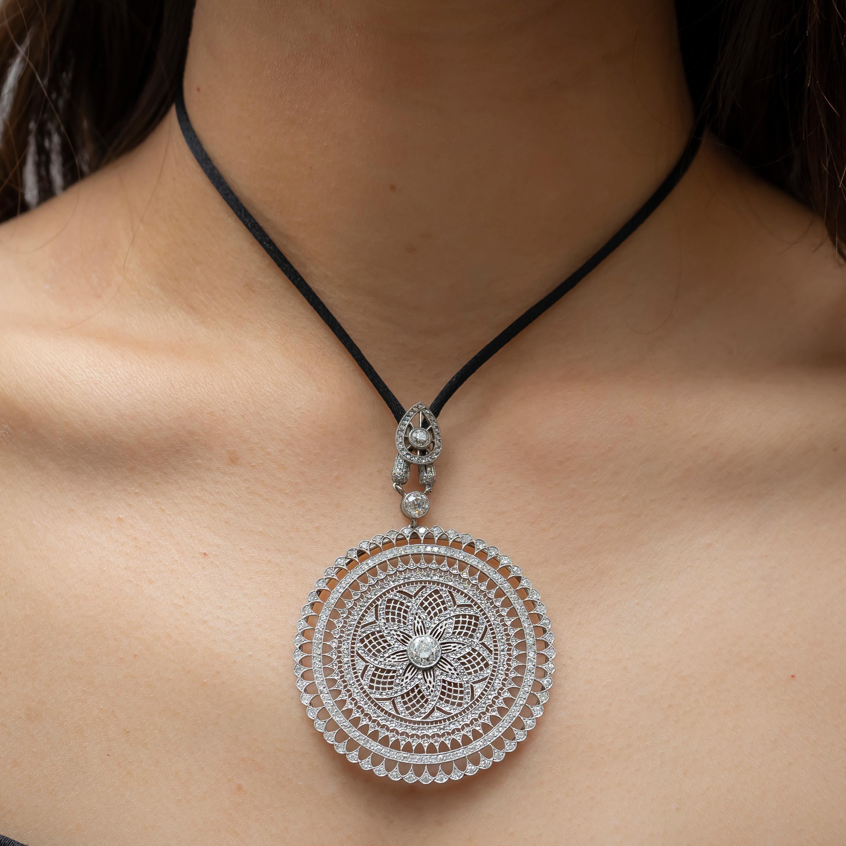 A modern, Edwardian style mandala diamond pendant, set with a central old-cut diamond, weighing 1.08ct, surrounded by 3.21ct of rose-cut and old-cut diamonds, on a lace like background, mounted in platinum, with millegrain edges on a black cord,