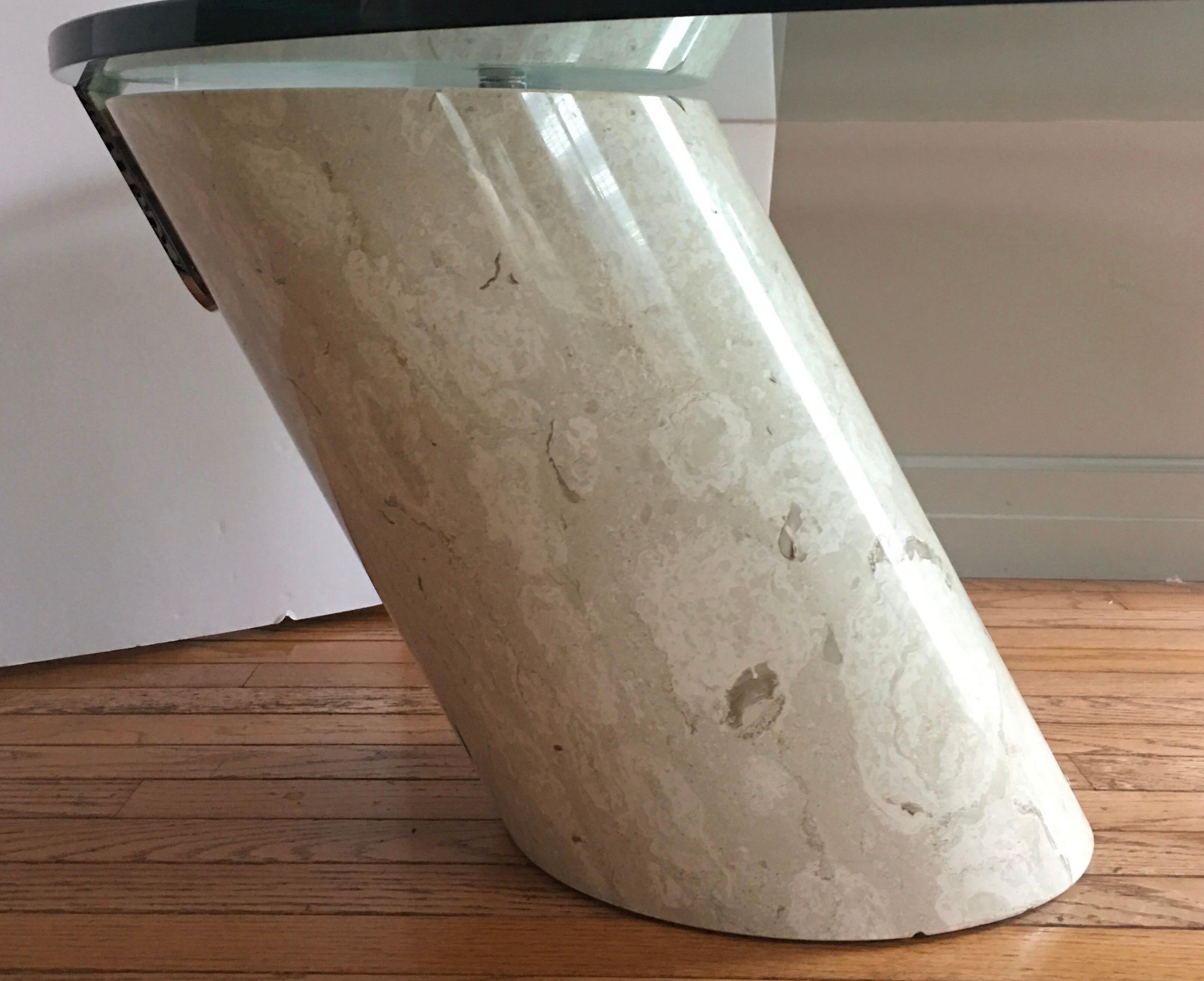 1970s modern Italian cantilevered coffee table with thick oval glass top supported by a solid cream/beige tone marble column base. The thick clear glass oval top is held in place with a chromed clip and studs. Glass top is removable. Cocktail table