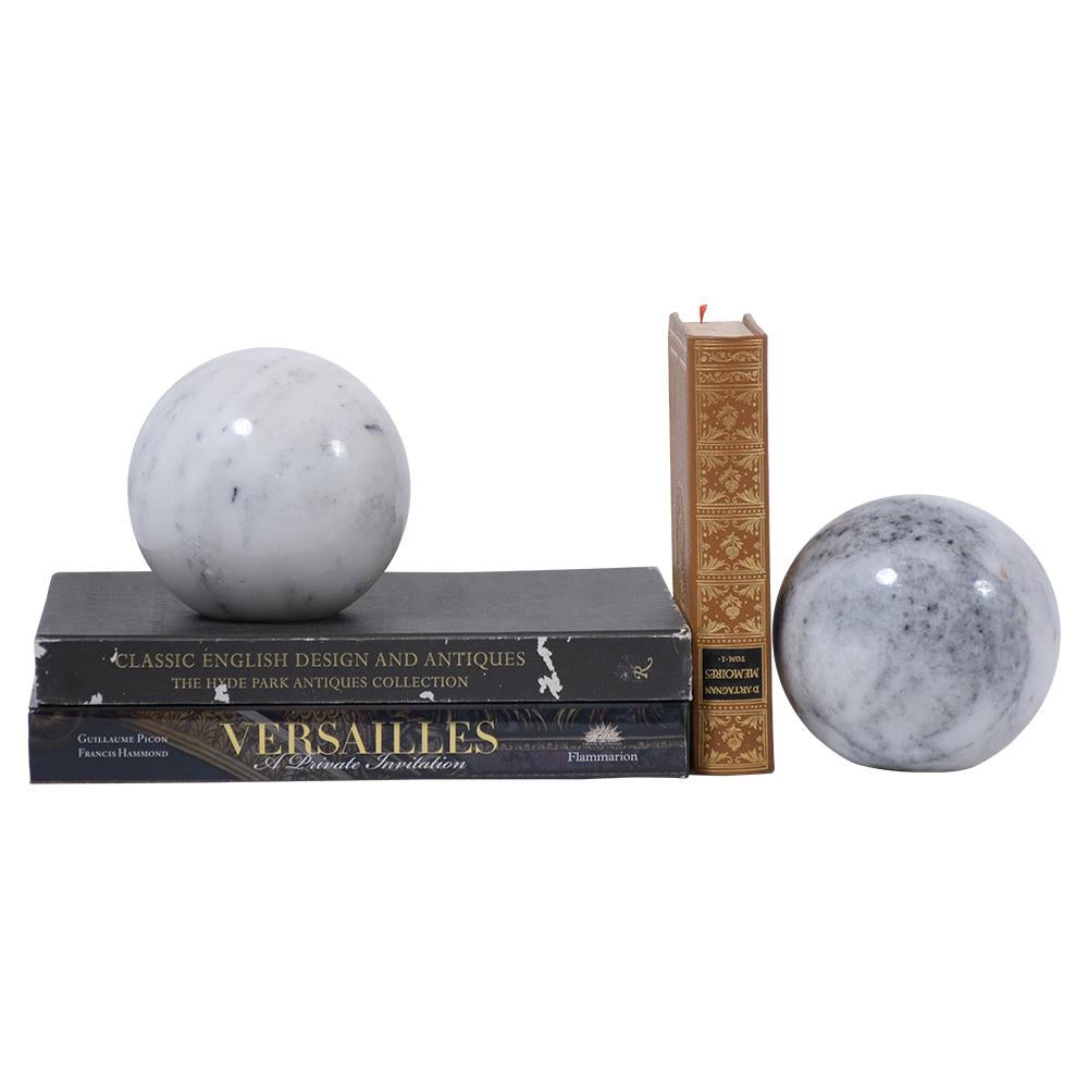 A unique pair of modern decorative bookends beautiful made out of a white Carrara marble and feature a handcrafted sphere shape. These bookends have been polished, are eye-catching, and the perfect addition to any office or home decor.