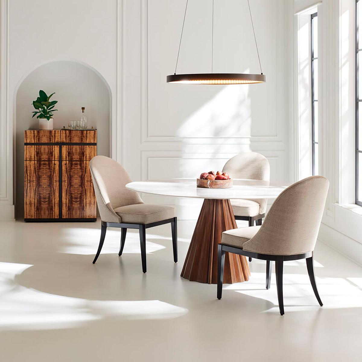 Dining table with a carved walnut base.  Designed with a reverse bevel, its veined white marble top creates the illusion of a thin stone resting on its conical base. Intimate and intentional, it elevates entertaining and quiet evenings in.