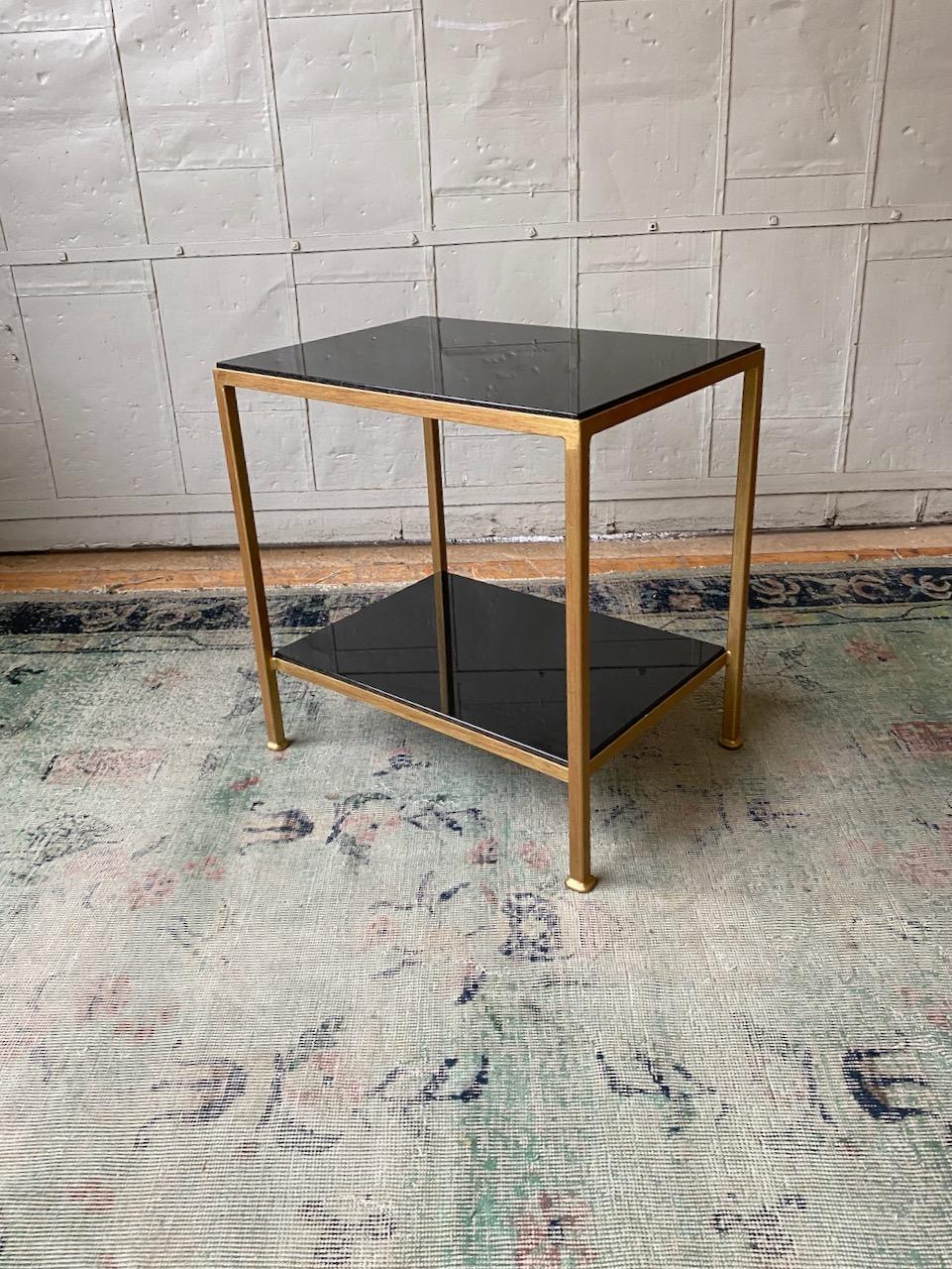 This well proportioned side table features an iron frame in a hand distressed gold finish with an undercoat of Venetian red. The shelves are polished absolute black granite. This is a floor sample from our discontinued Reeditions line. The sample is