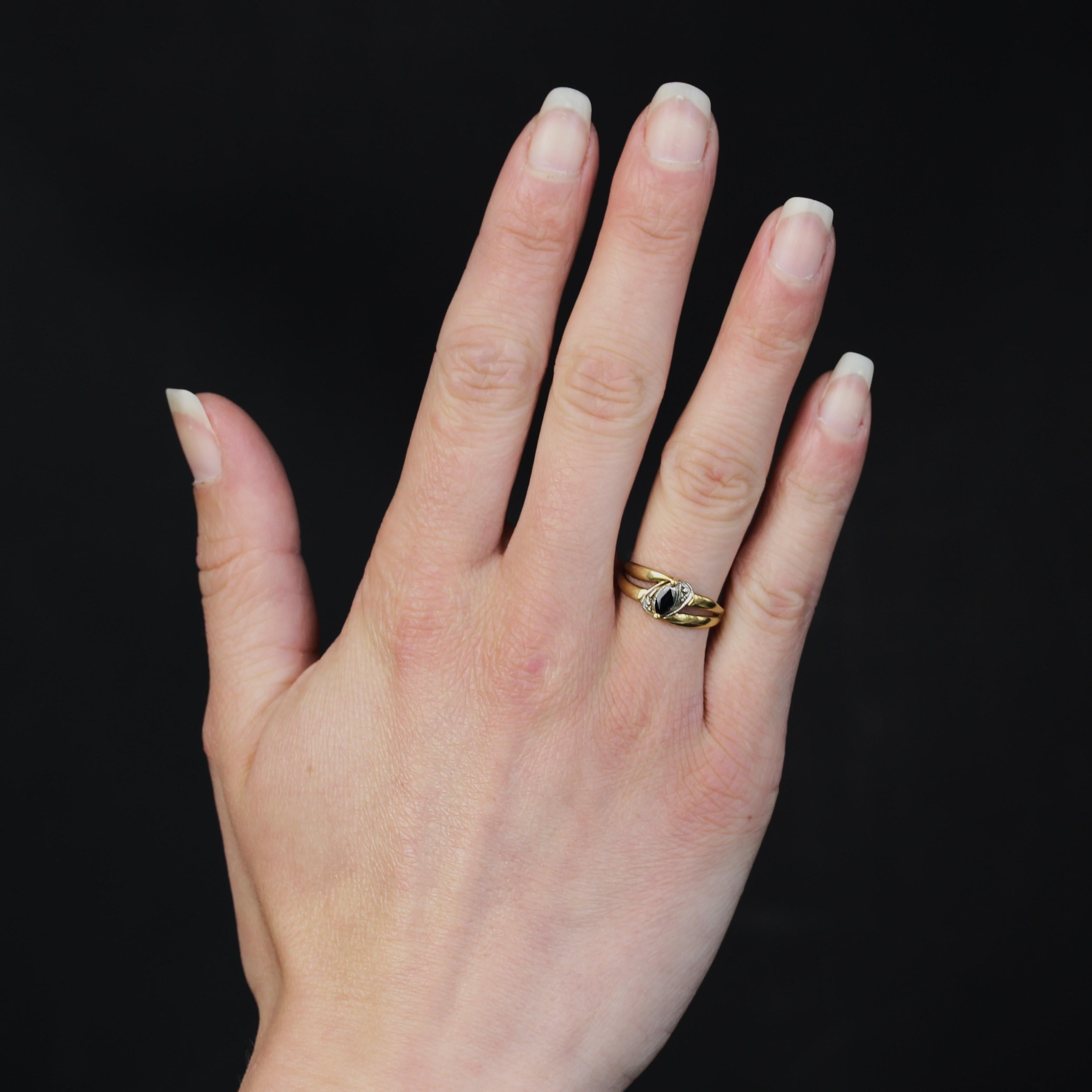 Ring in 18 karat yellow and white gold, eagle head hallmark.
This yellow gold ring is set with a central navette-cut sapphire in an asymmetrical diamond-cut setting in white gold. Two flat rings form the setting and meet at the base to form a single
