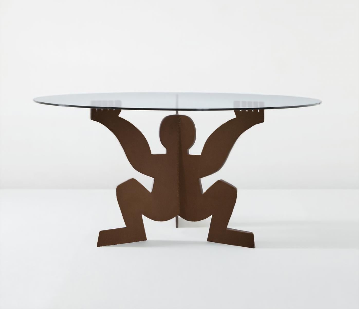 Dining table designed by Maurizio Cattelan in 1991 as a gift for Dilmos. 
Composed of a glass top and a base in crude iron depicting the form of the 