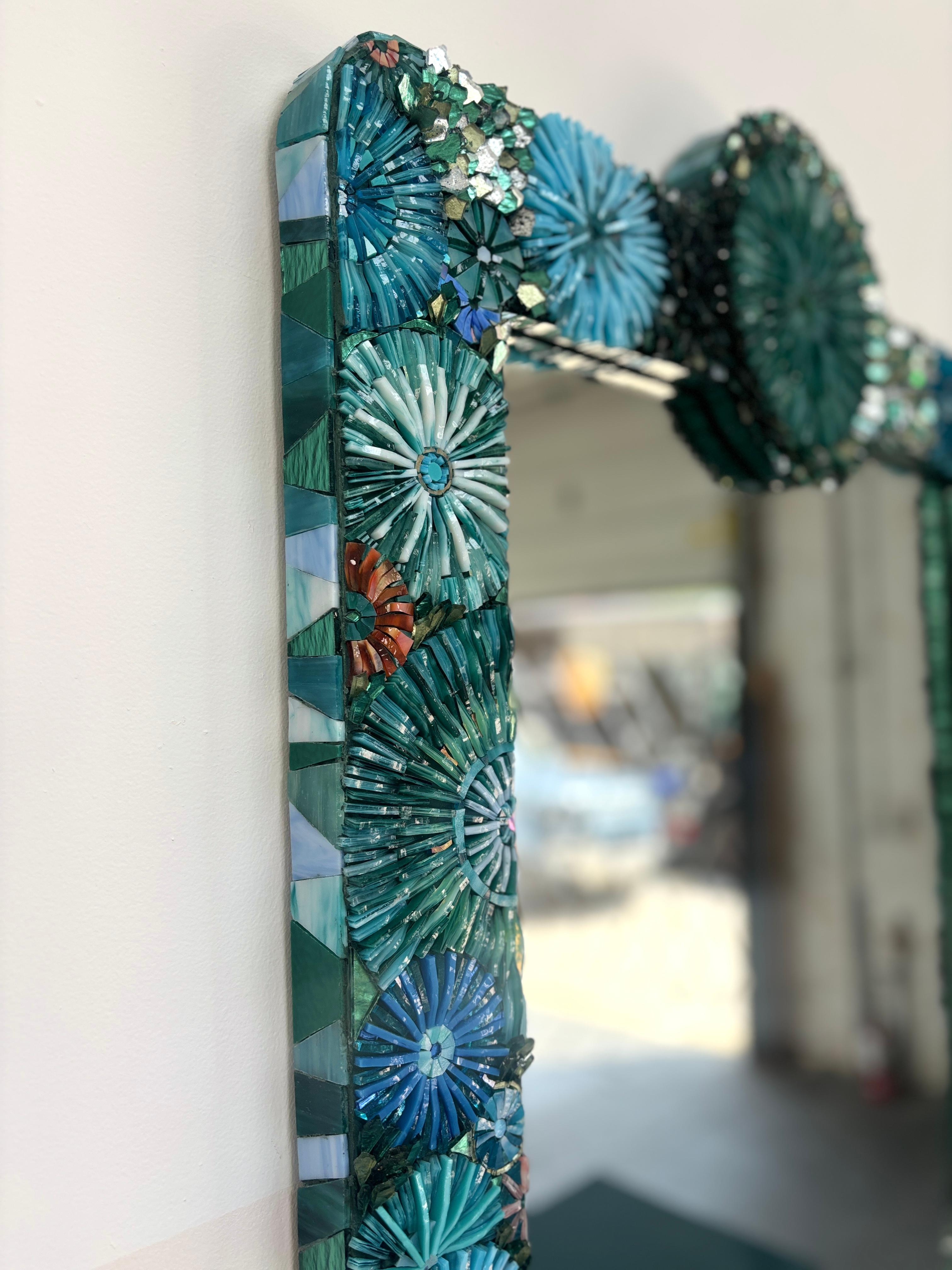 El Espejo moderno con mosaico de sirena de Ercole Home presenta mosaico de vidrio cortado a mano en tonos turquesa, verde azulado, azul francés, coral y plateado en un diseño de flores y escamas. 

Tamaños y acabados personalizados