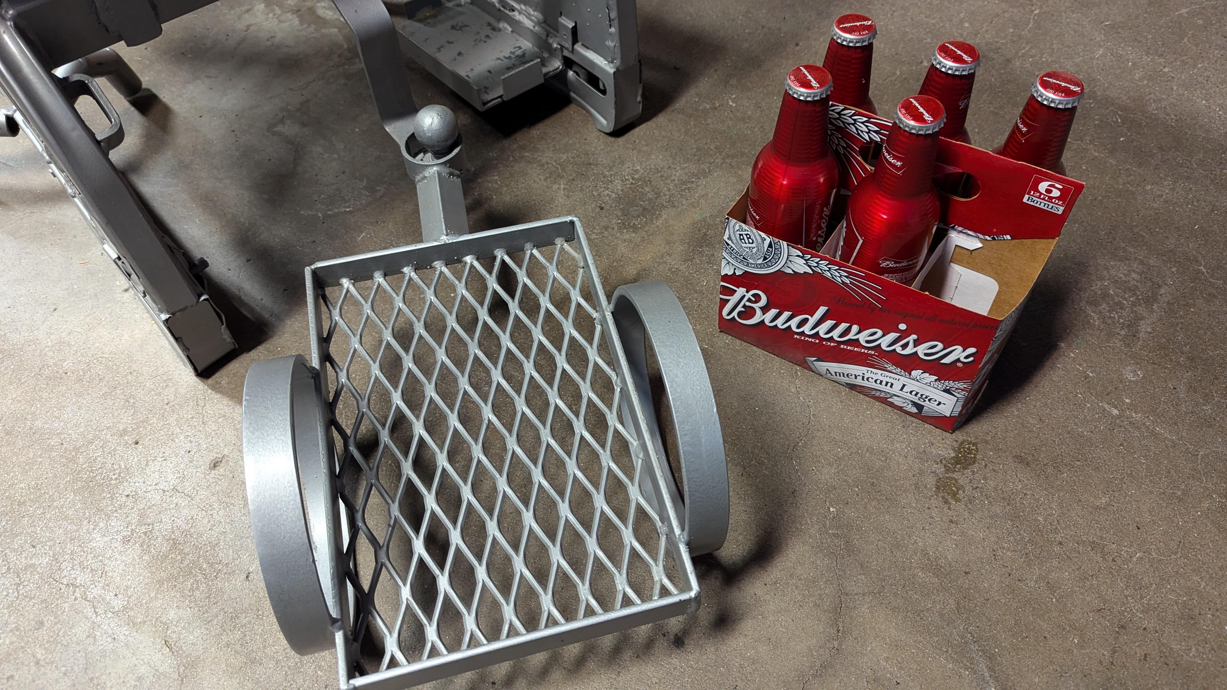 Scultura in metallo di Modern Art con la visione di un alieno industriale con piedi, testa, corpo, mani, occhi e bocca, che traina un piccolo rimorchio per la birra.  Un pezzo di conversazione artistico per la tua casa o il tuo ufficio.