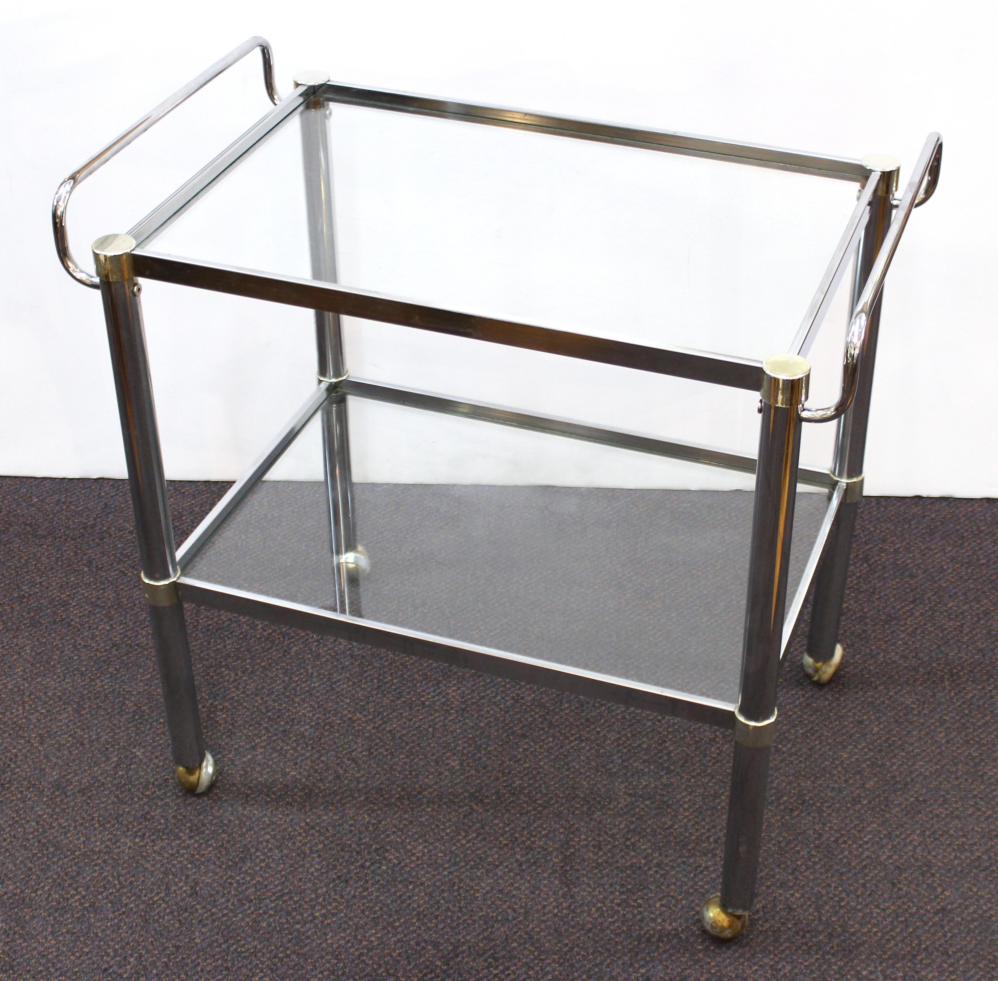 Modern chromed metal serving cart or bar cart with two glass levels and handle bars on front and back side. The piece is in good vintage condition with age-appropriate wear.