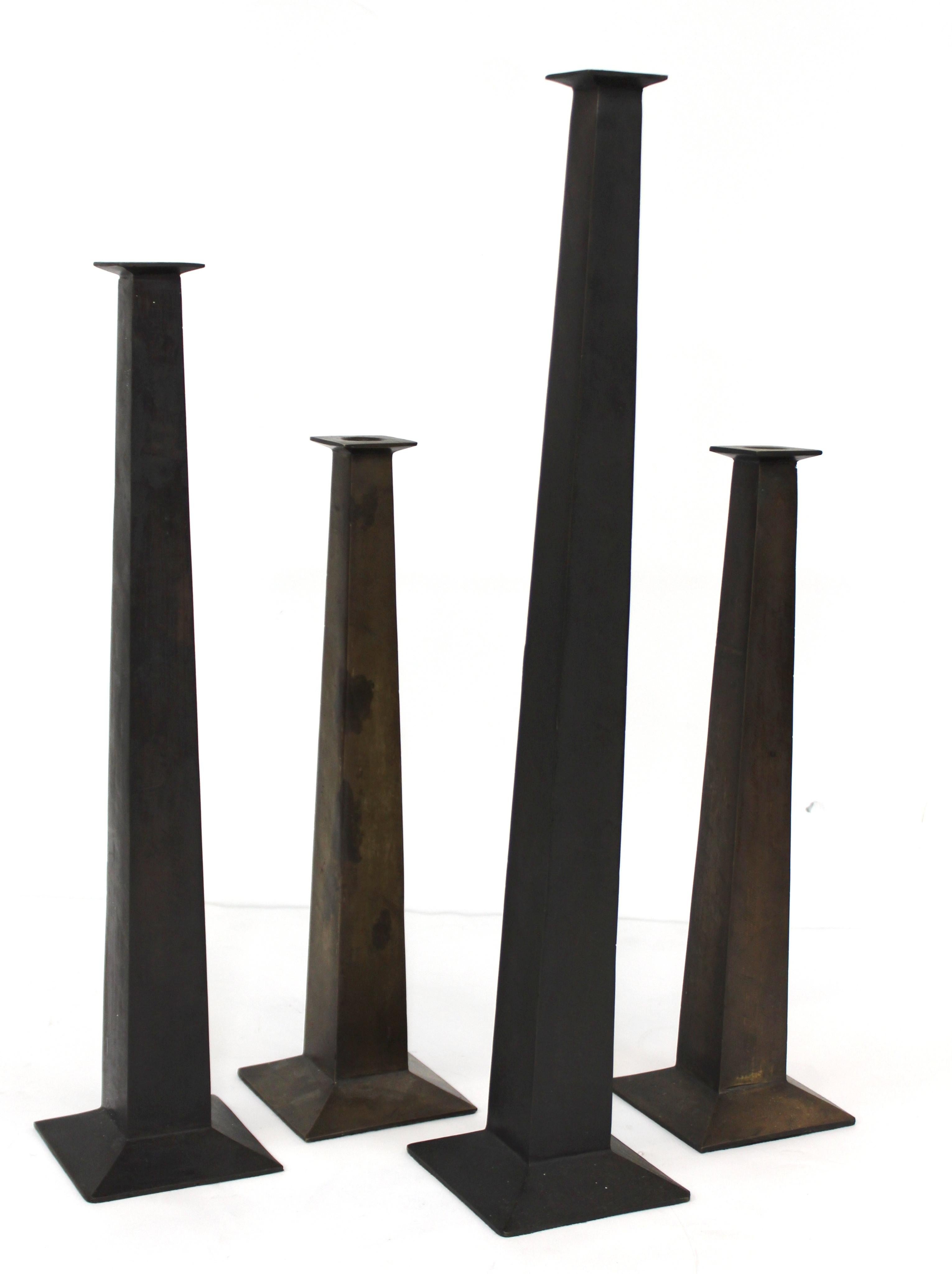Modern metal set of four individual candlesticks in three different height sizes with a rough metal texture. The set is in great vintage condition with age-appropriate wear.